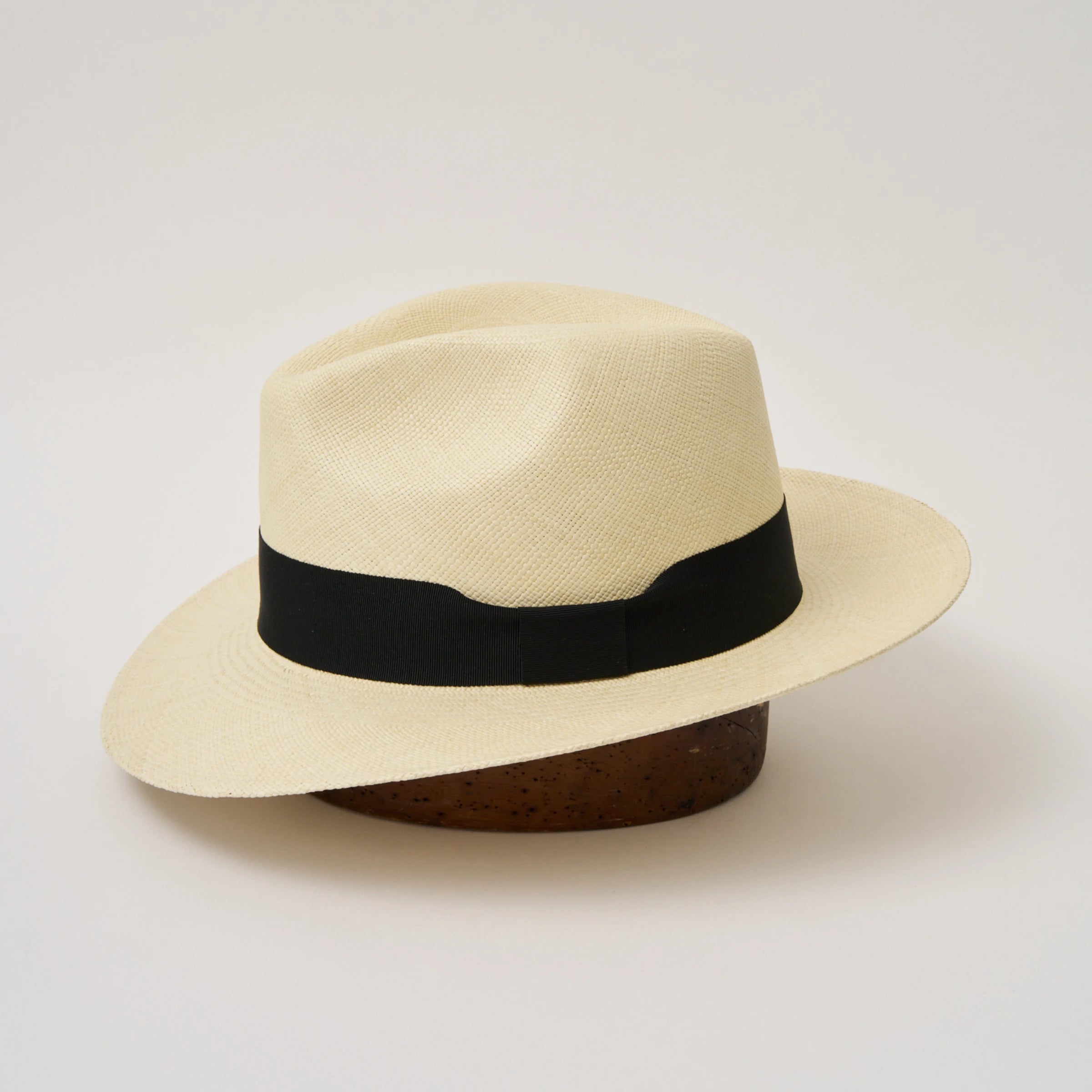 Studio image of the Camilo Classic Fino Natural coloured Panama Hat with Black trim taken from the side, showing the brim shape and ribbon finish.
