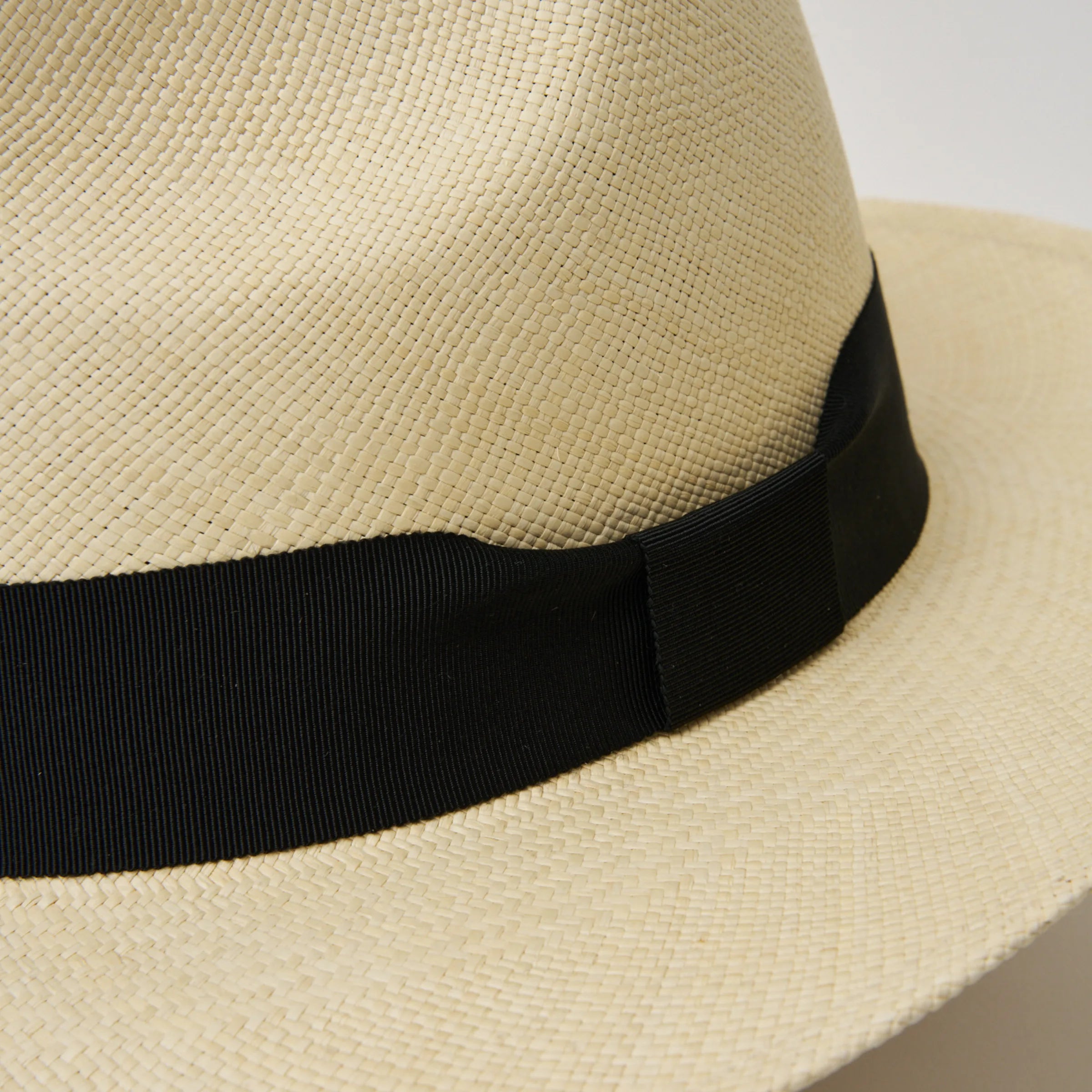 Studio image, closeup of the ribbon detail on the side of the Camilo Classic Fino Natural coloured Panama Hat with Black trim.