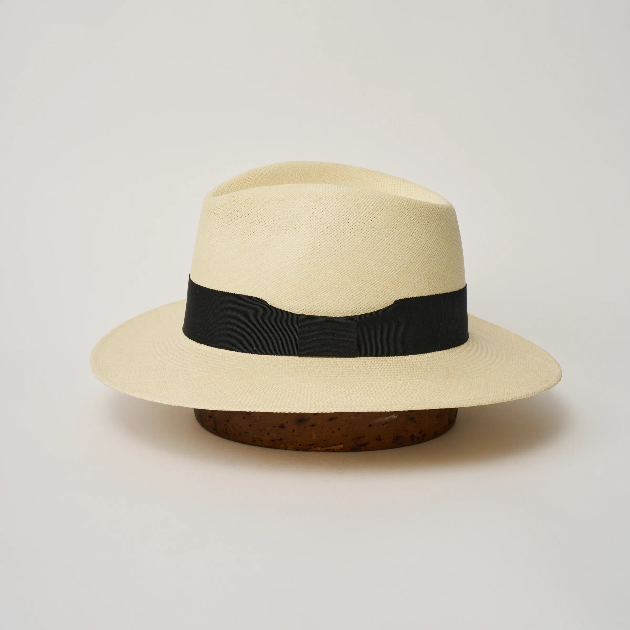 Studio image of the Camilo Executive Fino
Natural coloured Panama Hat with Black trim shown from the side, showing the brim shape and ribbon finish.