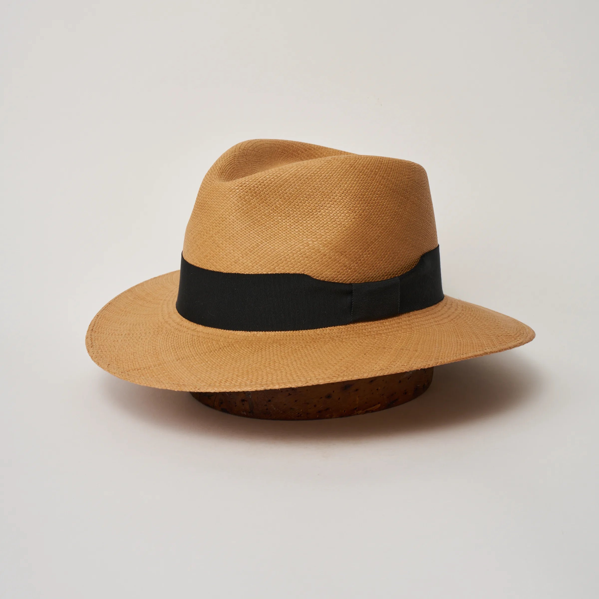 Studio image of the Camilo Executive Fino Toffee coloured Panama Hat with Black trim, angled showing the crown shape, front crease and ribbon details.