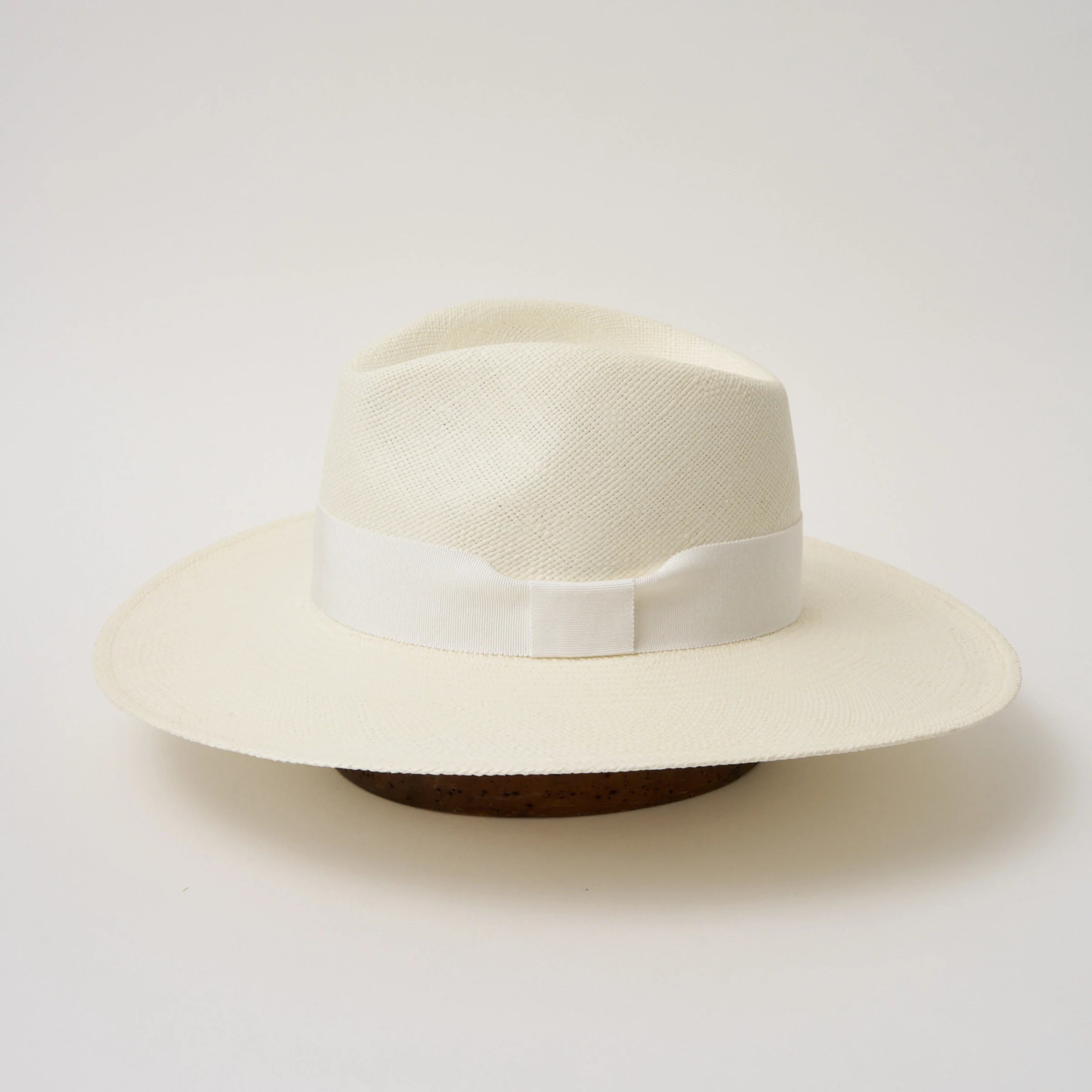 Studio image of the Camilo Oro Cream coloured Panama Hat with White trim taken from the side, showing brim and ribbon finish.