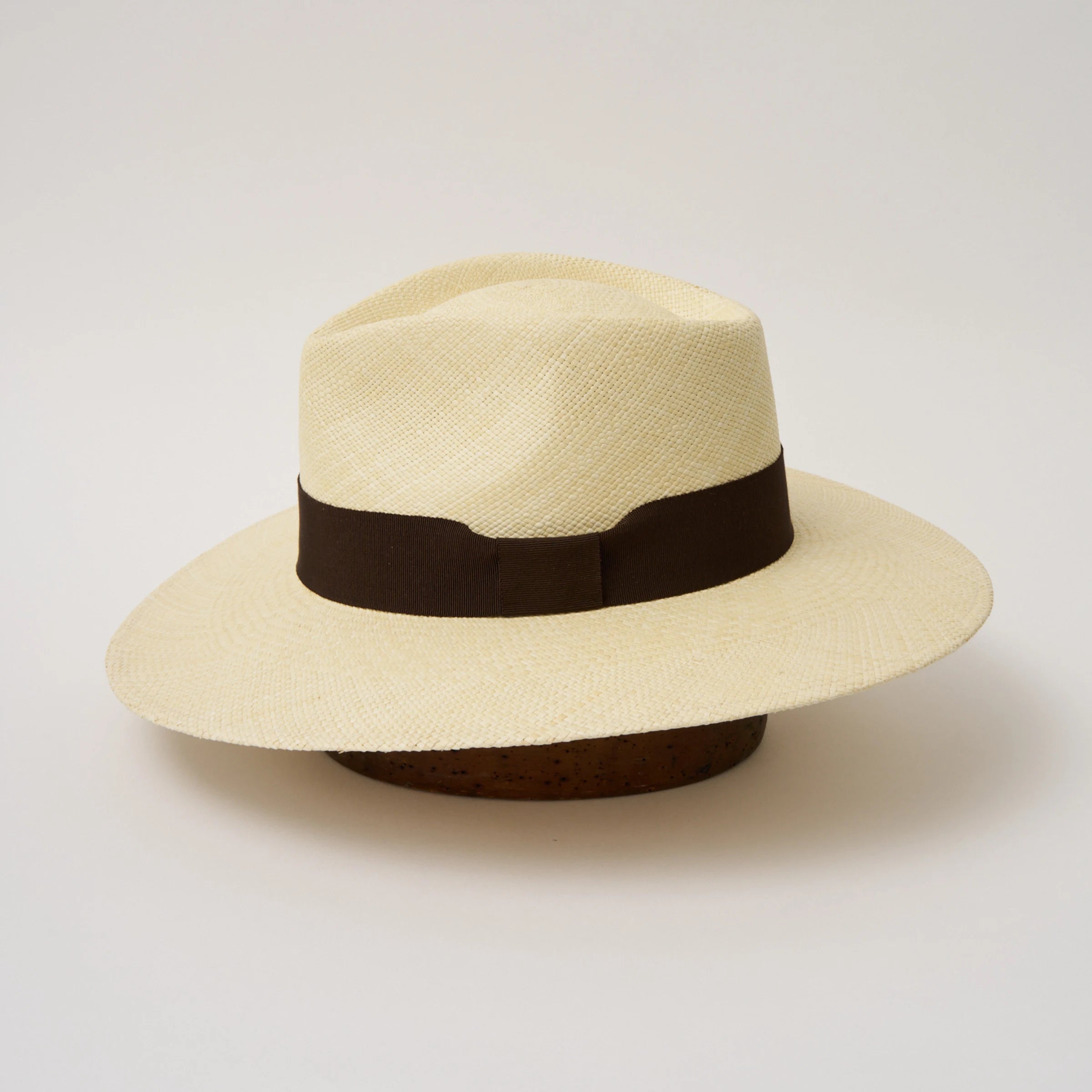 Studio image of the Camilo Vita Natural coloured Panama Hat with Chocolate trim taken from the side, showing brim and ribbon finish.