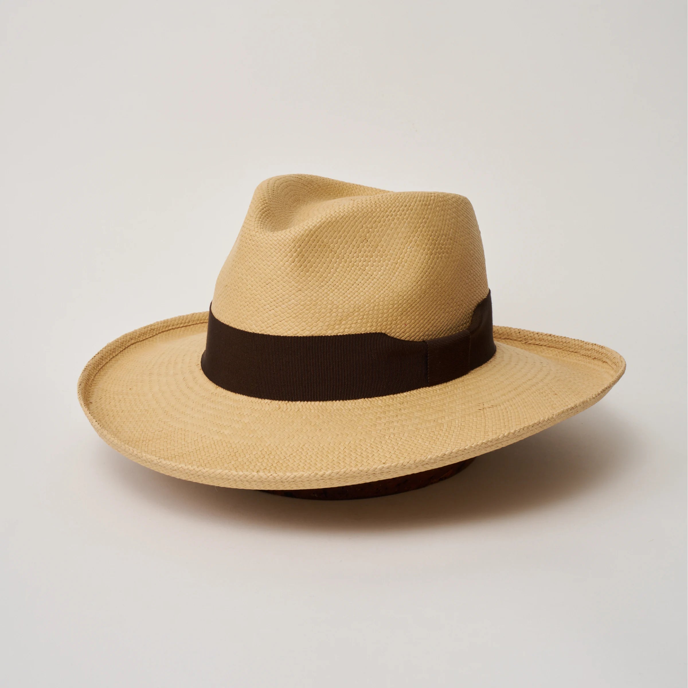 Studio image of the Camilo Grand Planter Sand coloured Panama Hat with Chocolate trim, angled showing the crown shape, front crease and ribbon details.