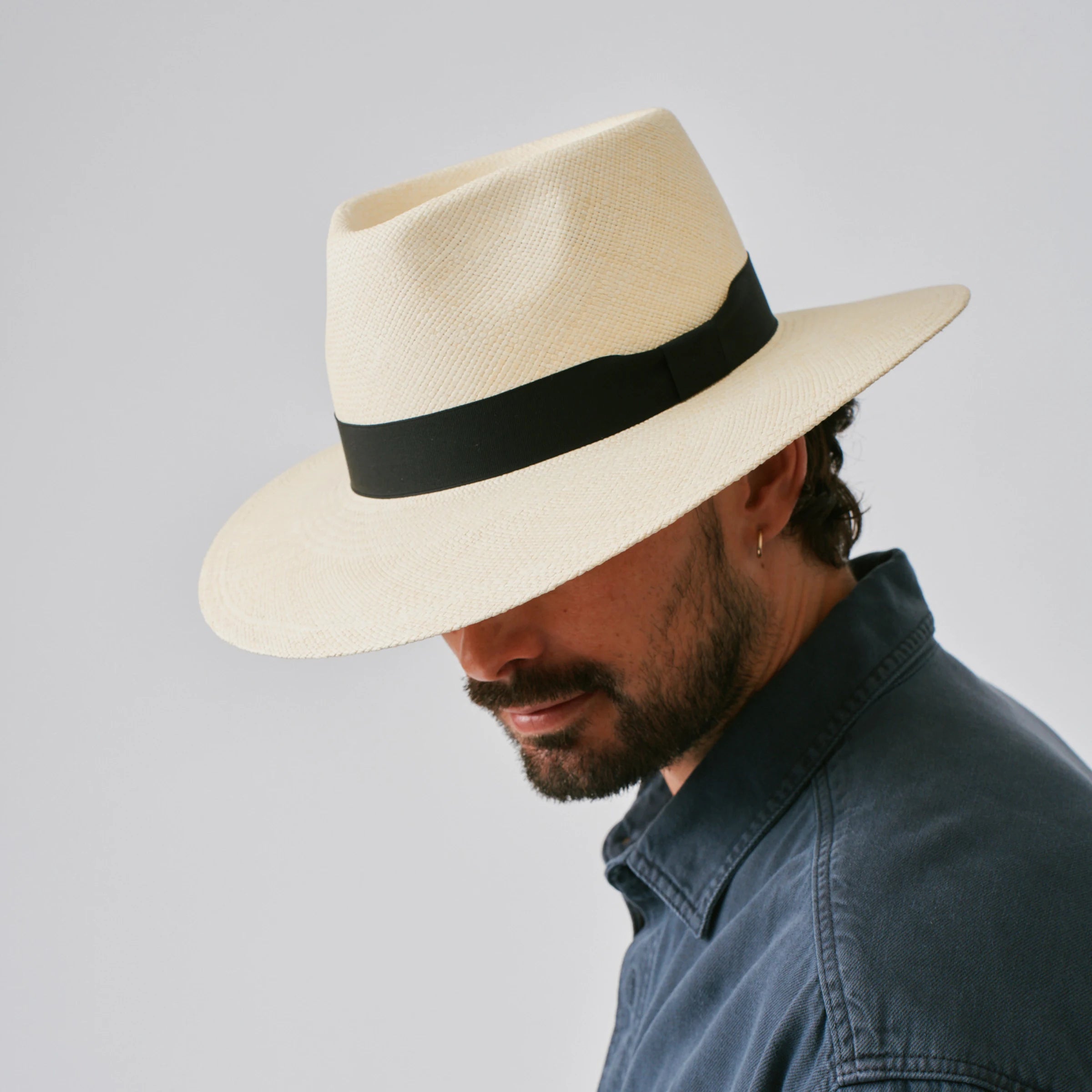 Man wearing a Country Natural / Black Panama hat against a plain background.