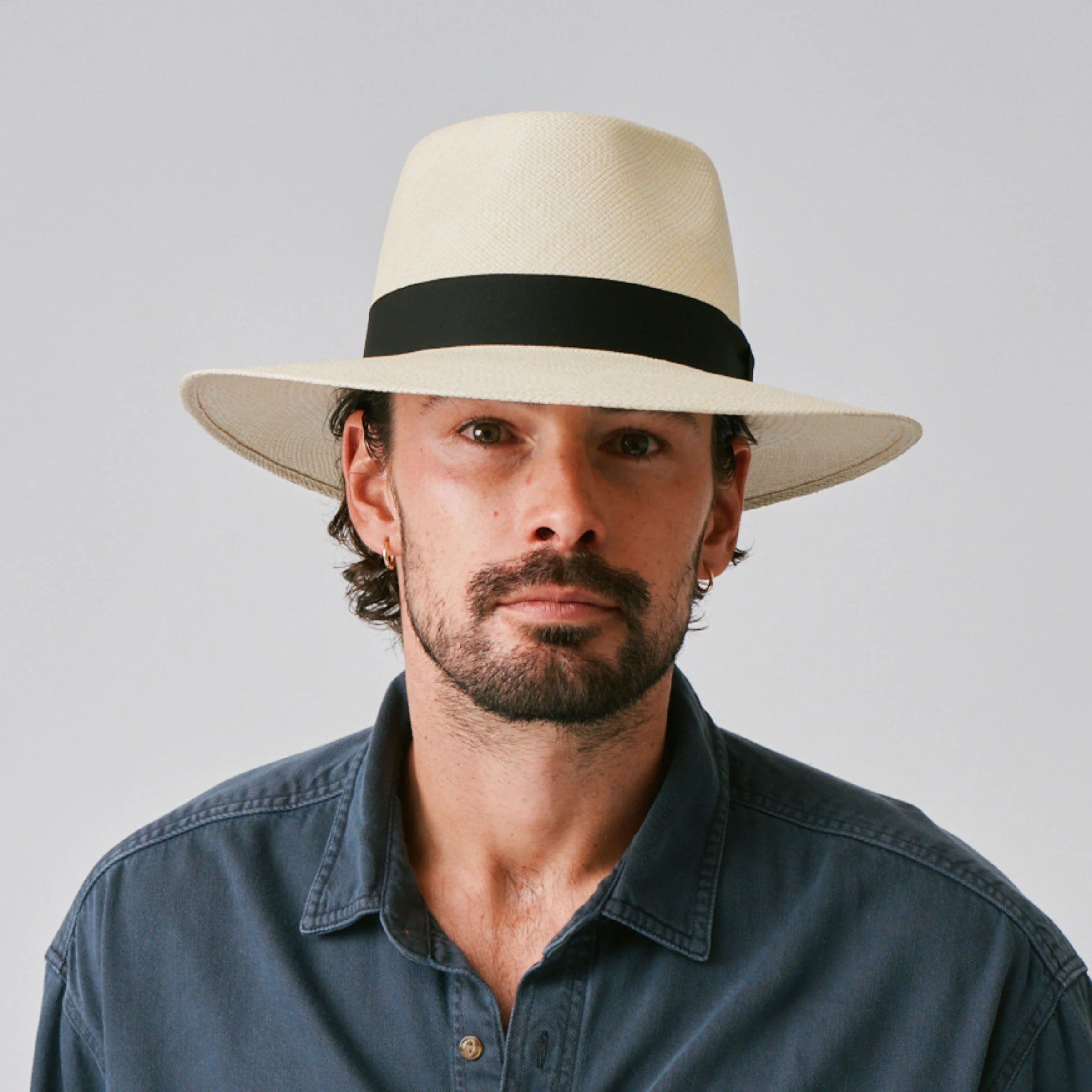 Man wearing a Country Natural / Black Panama hat and blue shirt against a plain background.