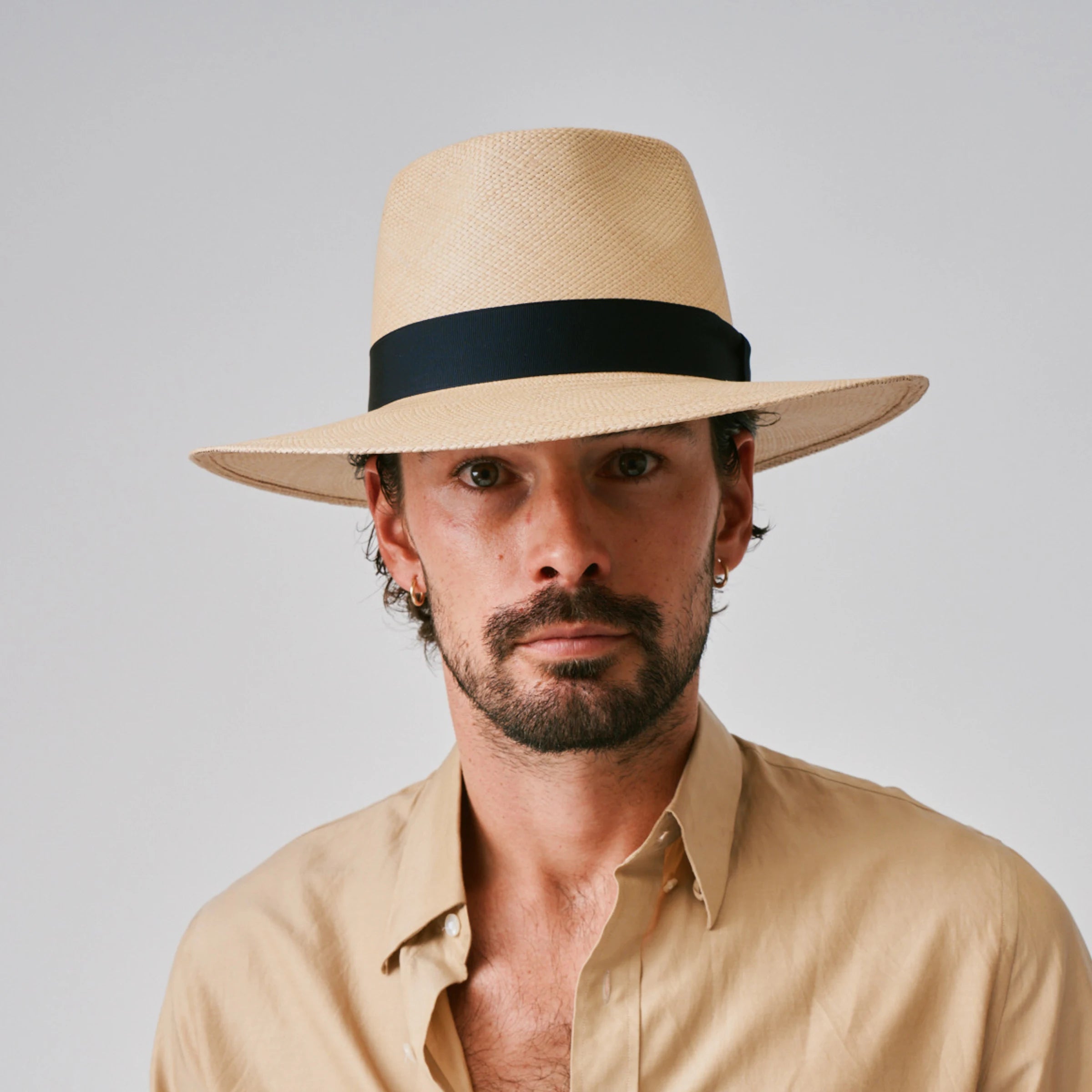 Man wearing a Country Sand / Marine Panama hat and a beige shirt against a plain background.