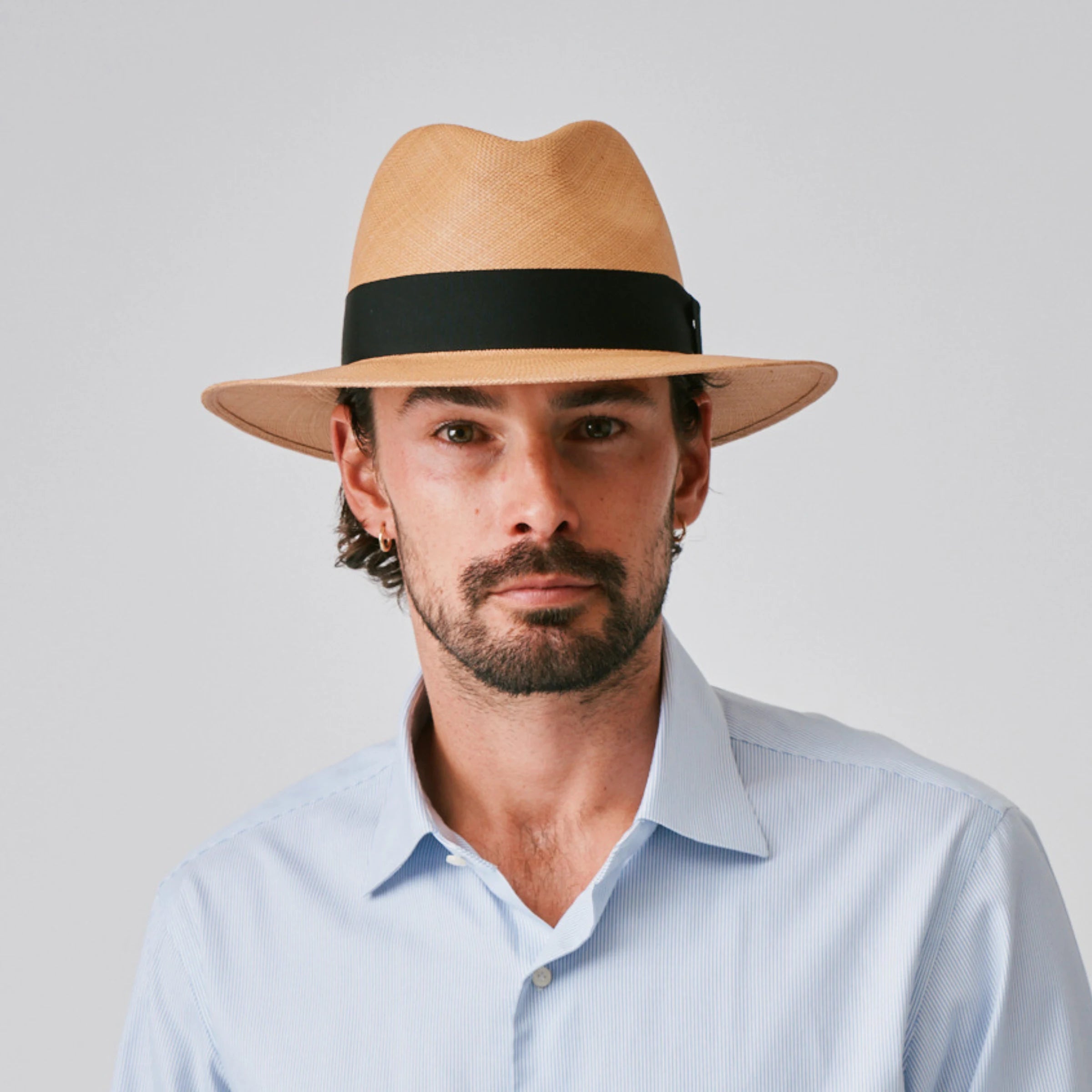 Man wearing a Executive Fino Toffee / Black Panama hat and blue shirt against a plain background.