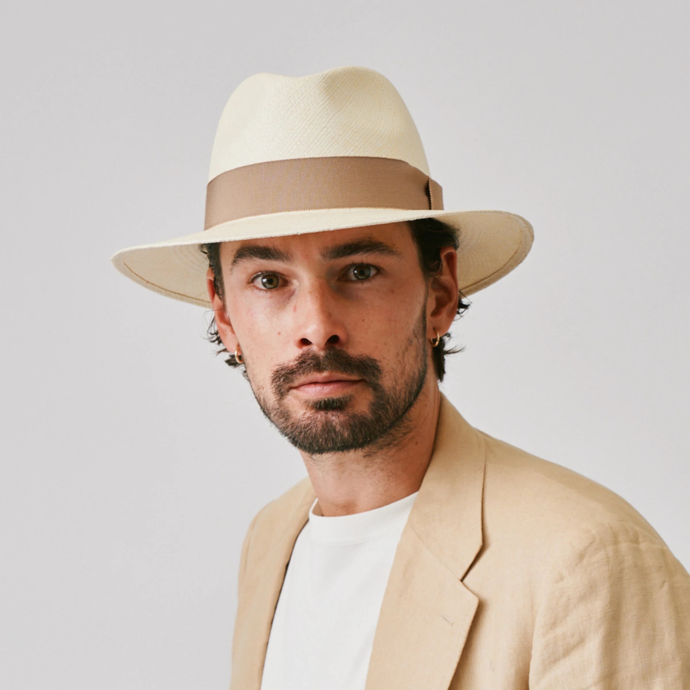 Man wearing a Executive Natural / Oat Panama hat and linen jacket against a plain background.