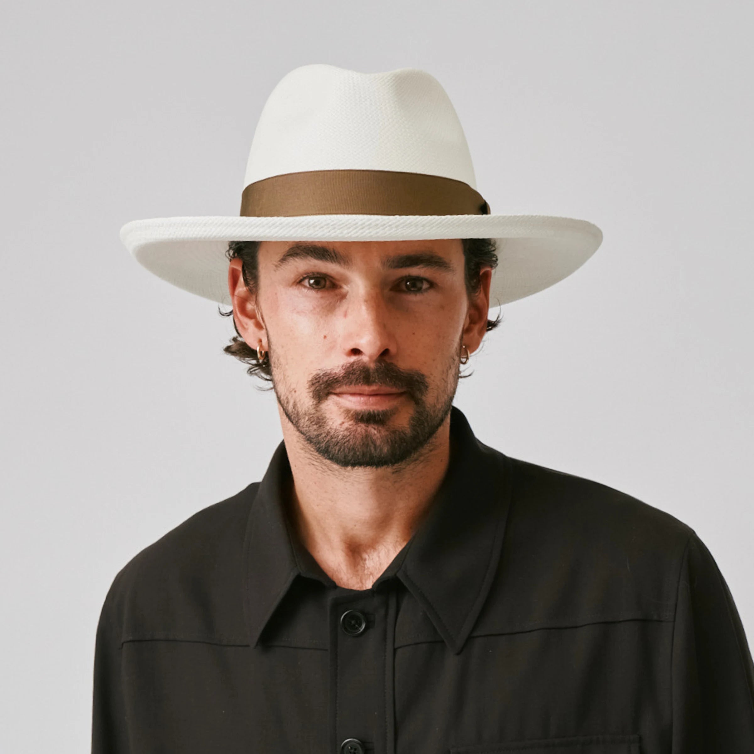 Man wearing a Grand Planter Cream / Fawn Panama hat and black shirt against a plain background.