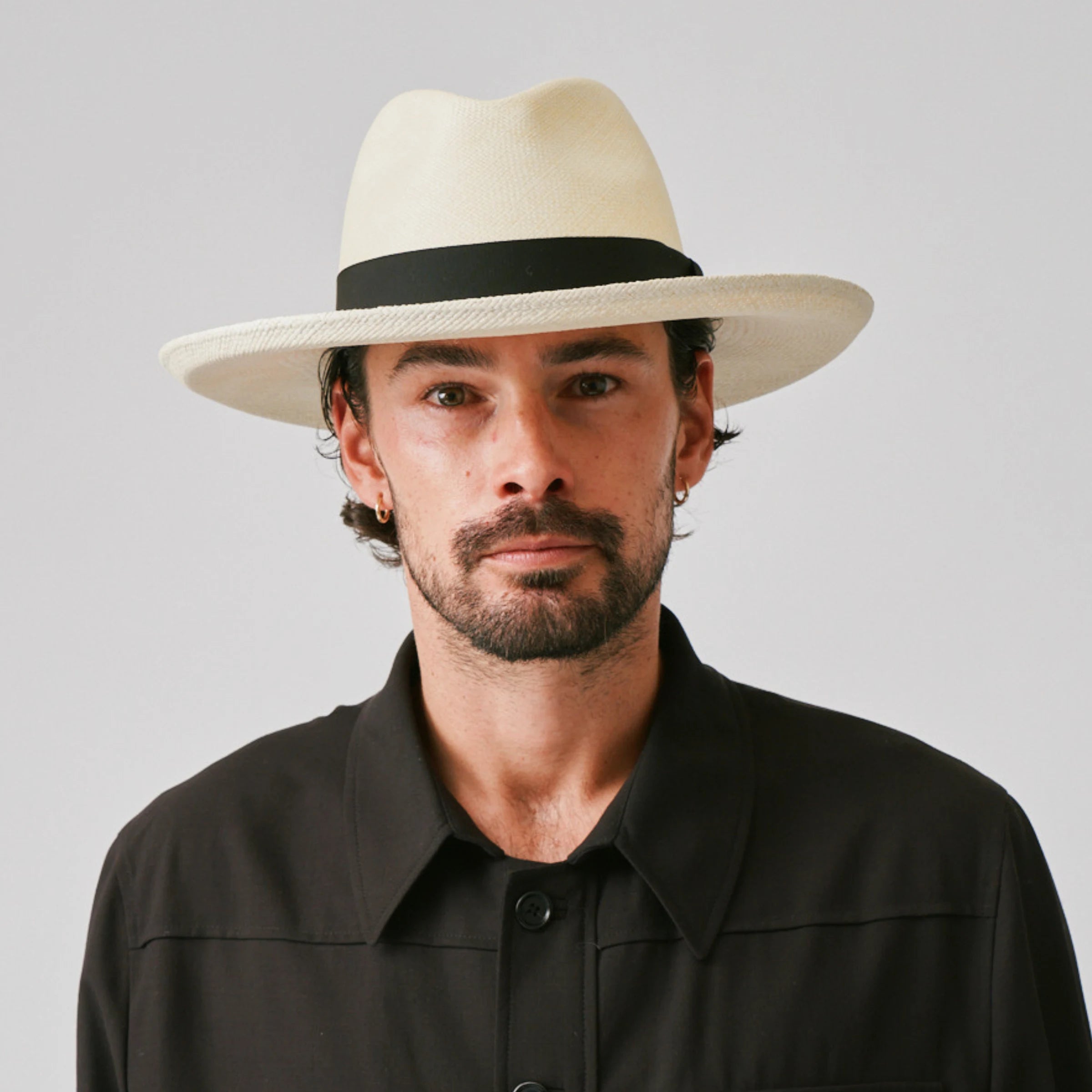 Man wearing a Grand Planter Natural / Black Panama hat and black shirt against a plain background.