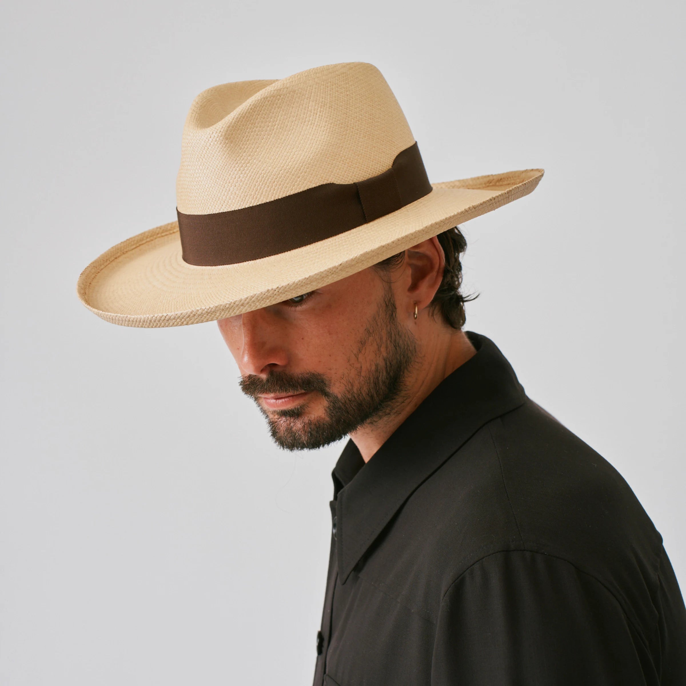 Man wearing a Grand Planter Sand / Chocolate Panama hat against a plain background.