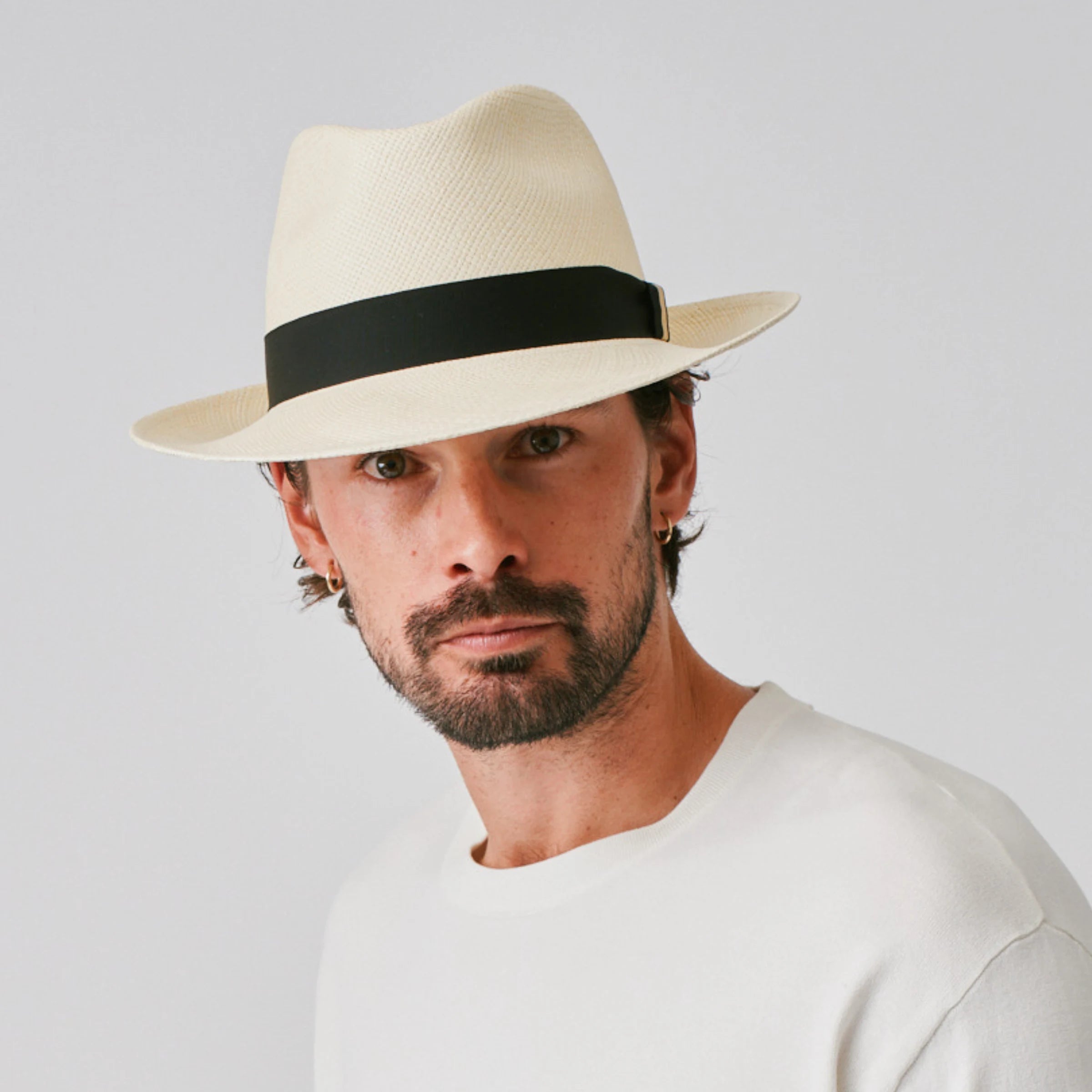 Woman wearing a New Fedora Natural / Black Panama hat and white top against a plain background.