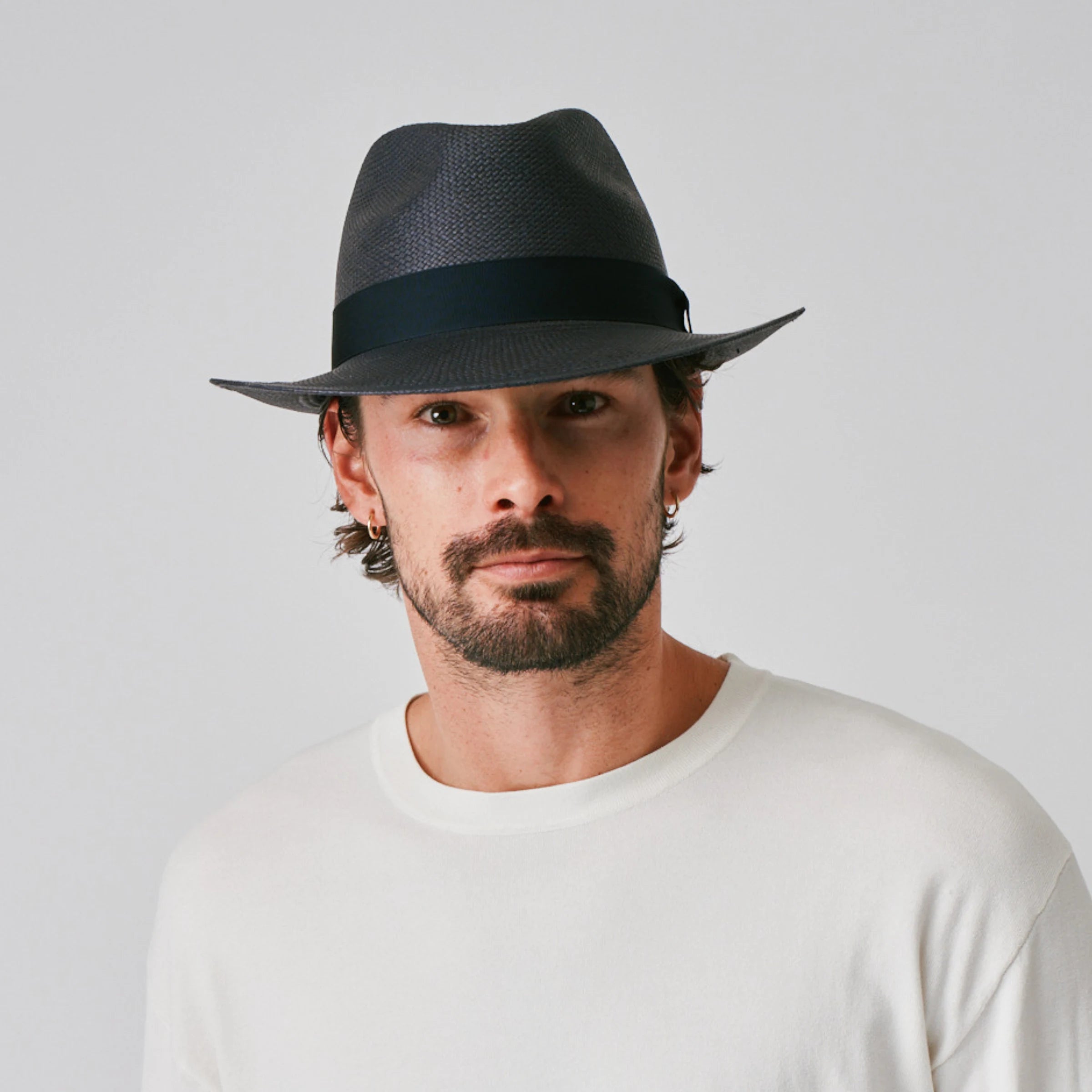 Man wearing a New Fedora Navy / Marine Panama hat and white shirt against a plain background.