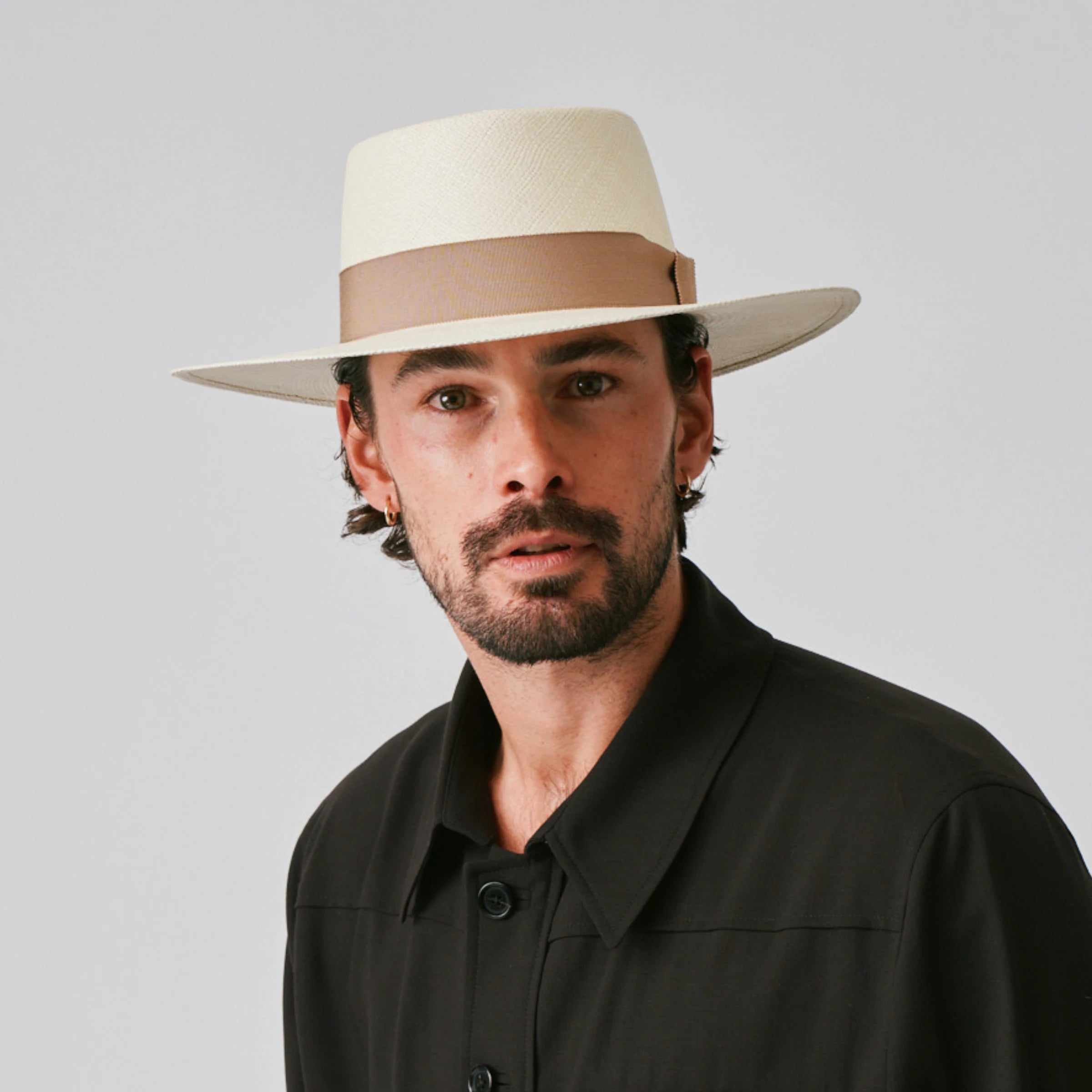Man wearing a Sol Natural / Oat Panama hat and black shirt against a plain background