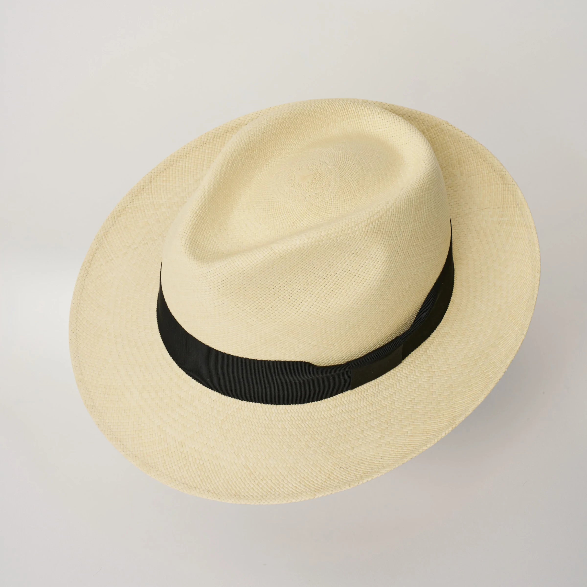 Studio image looking top-down, of the Camilo New Fedora Fino Natural coloured Panama Hat with Black trim, showing the crown shape and weave details.