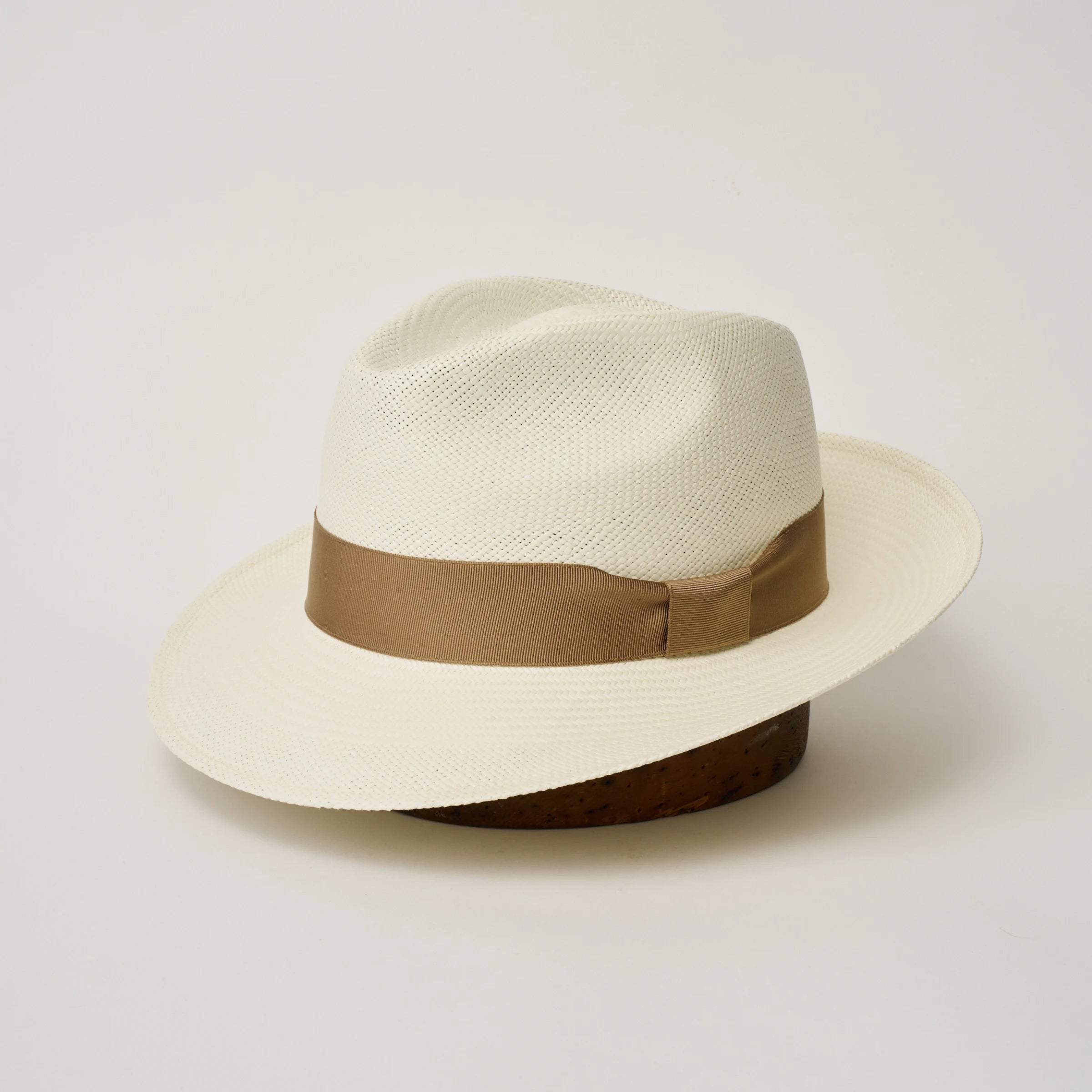 Studio image, three-quarter view of the Camilo New Fedora Cream coloured Panama Hat with Tan trim, showing the crown shape, front crease and ribbon trim.