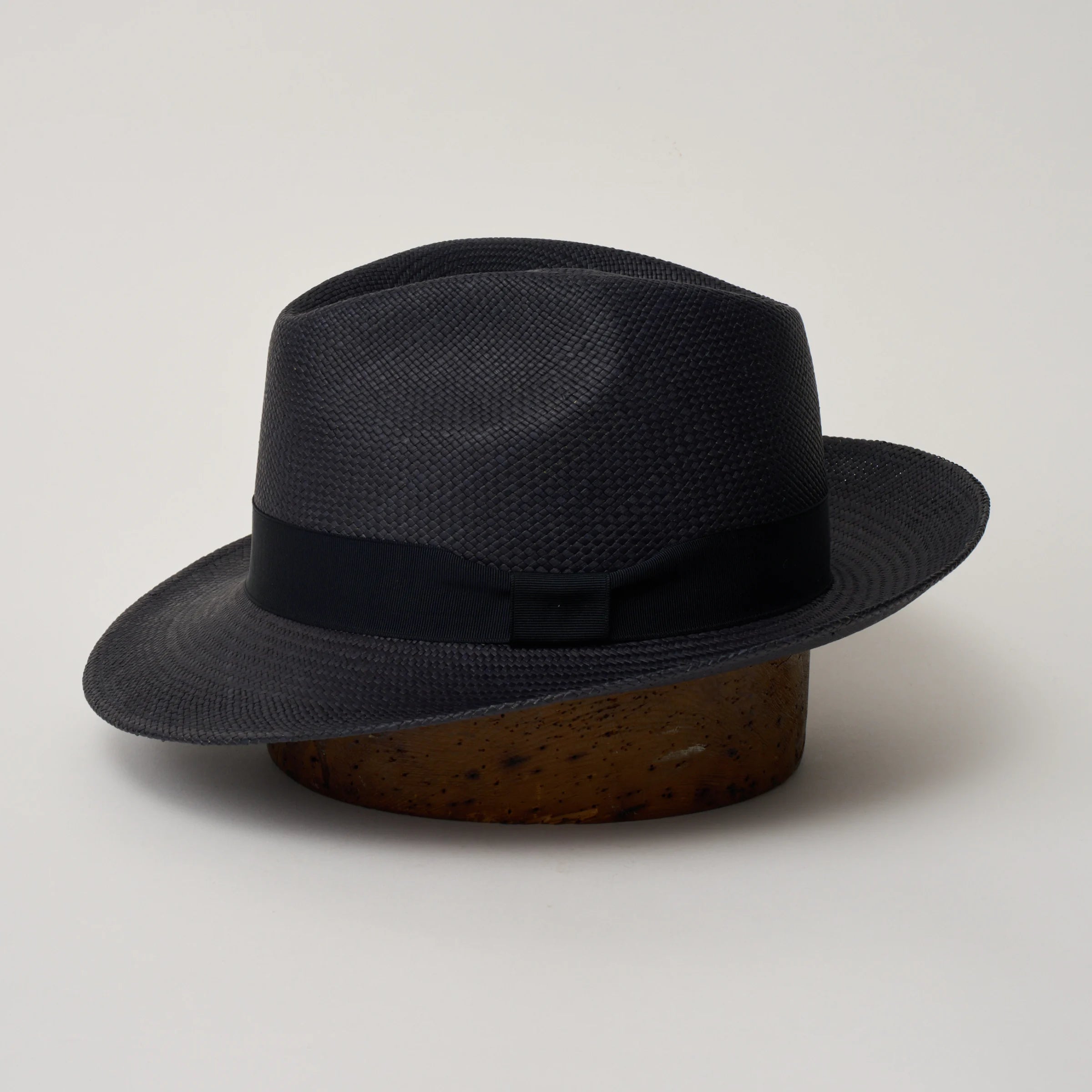 Studio image of the Camilo New Fedora Navy coloured Panama Hat with Marine trim shown from the side, showing the brim shape and ribbon finish.