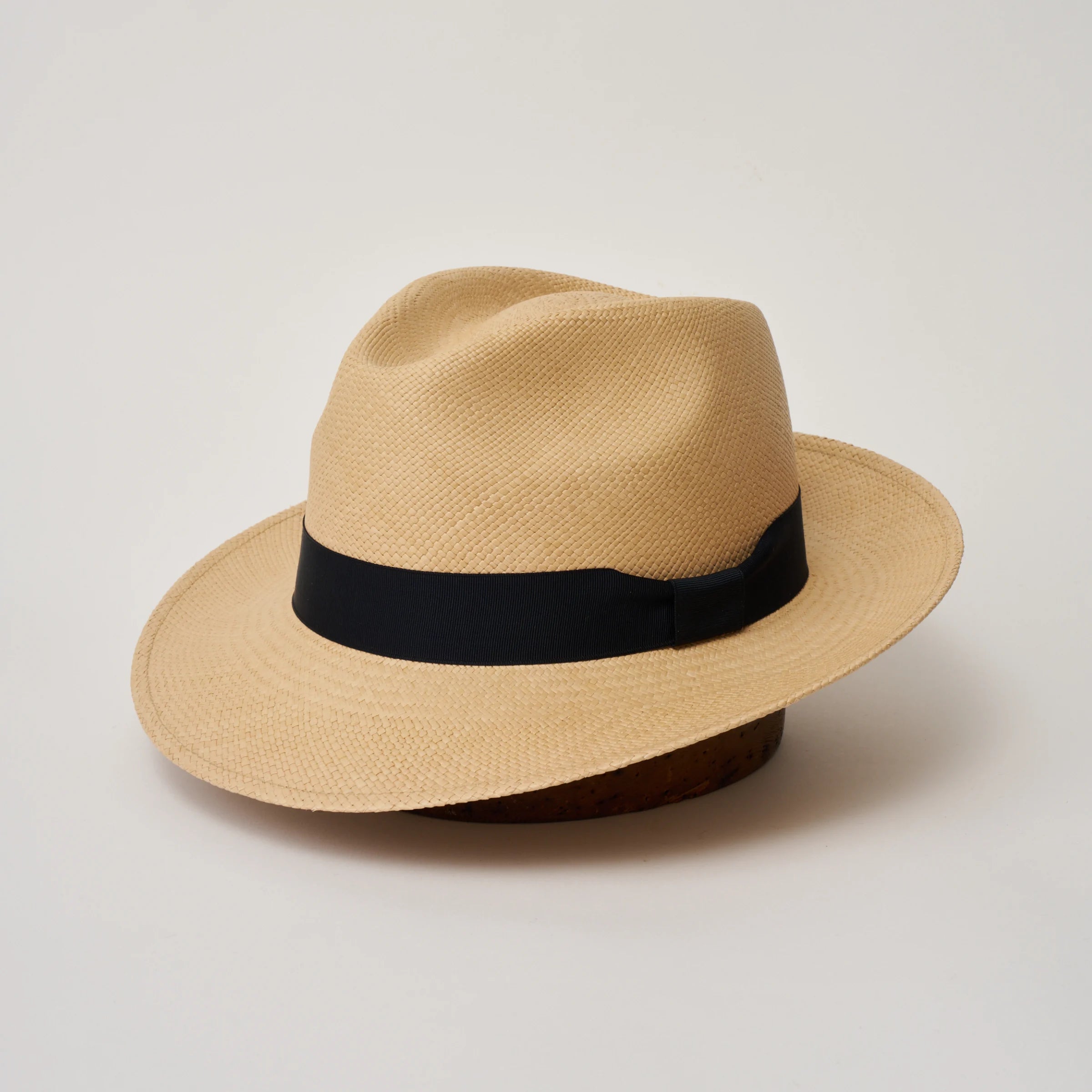 Studio image, three-quarter view of the Camilo New Fedora Sand coloured Panama Hat with Marine trim, showing the crown shape, front crease and ribbon trim.