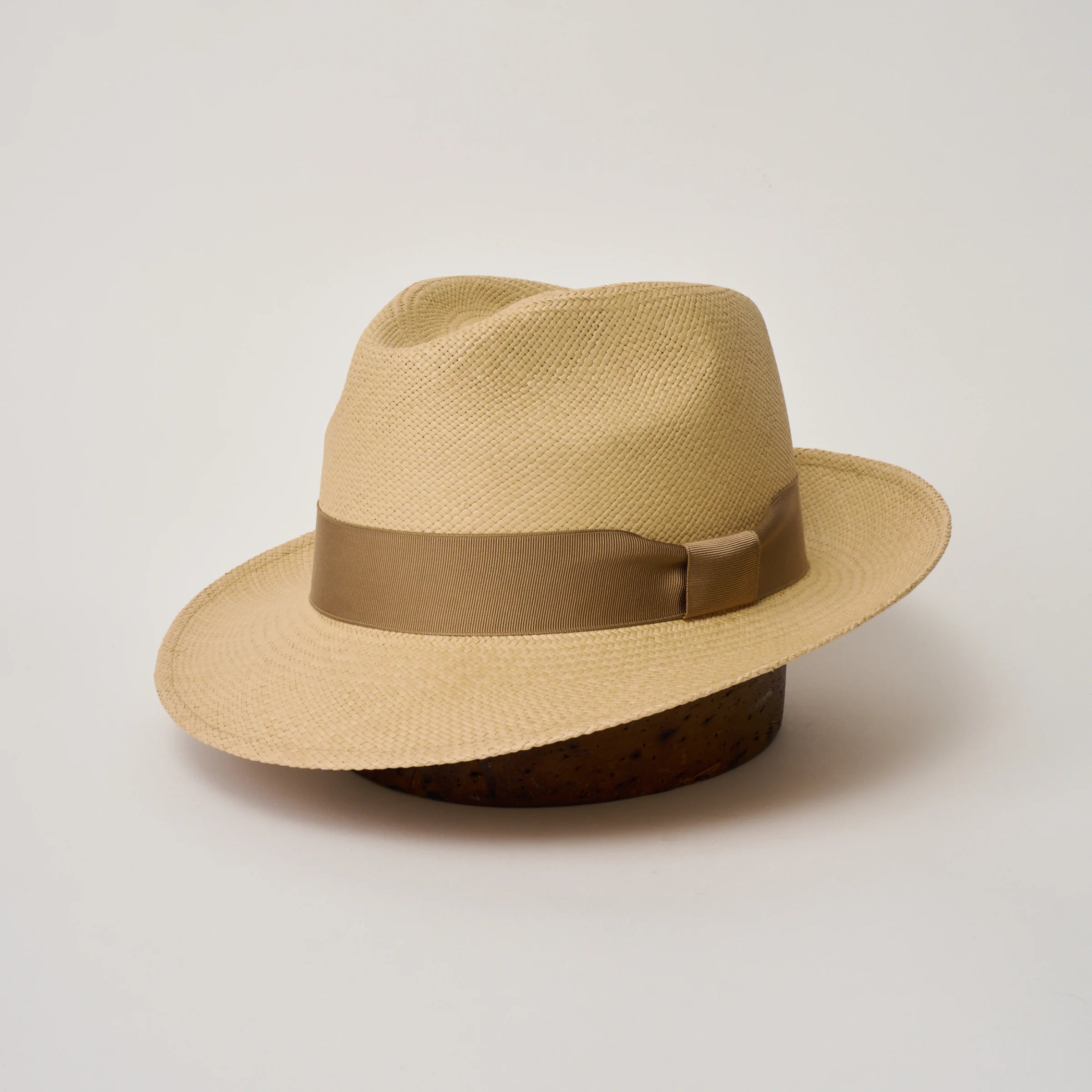 Studio image, three-quarter view of the Camilo New Fedora Sand coloured Panama Hat with Tan trim, showing the crown shape, front crease and ribbon trim.