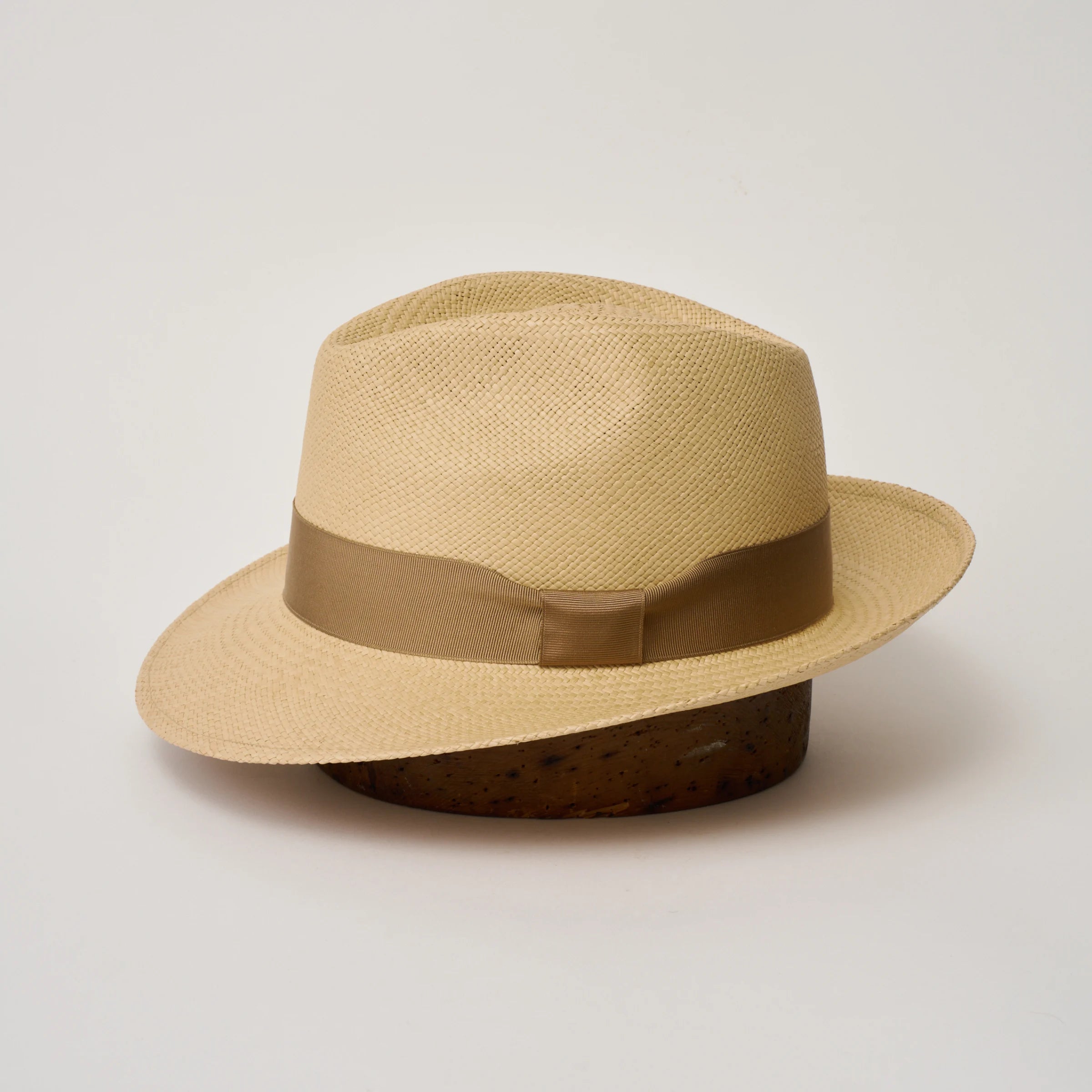 Studio image of the Camilo New Fedora Sand coloured Panama Hat with Tan trim shown from the side, showing the brim shape and ribbon finish.