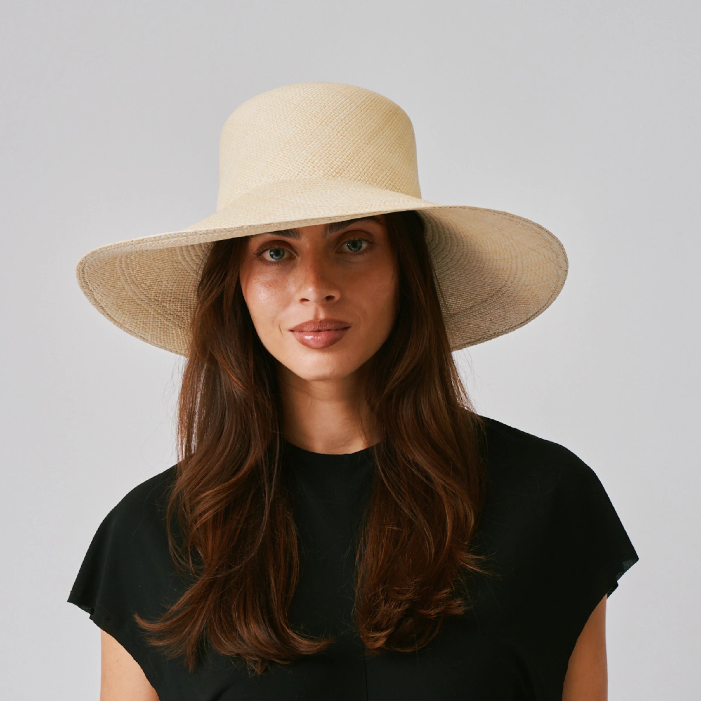 Woman wearing a Alba Natural Panama hat and black top against a plain background.