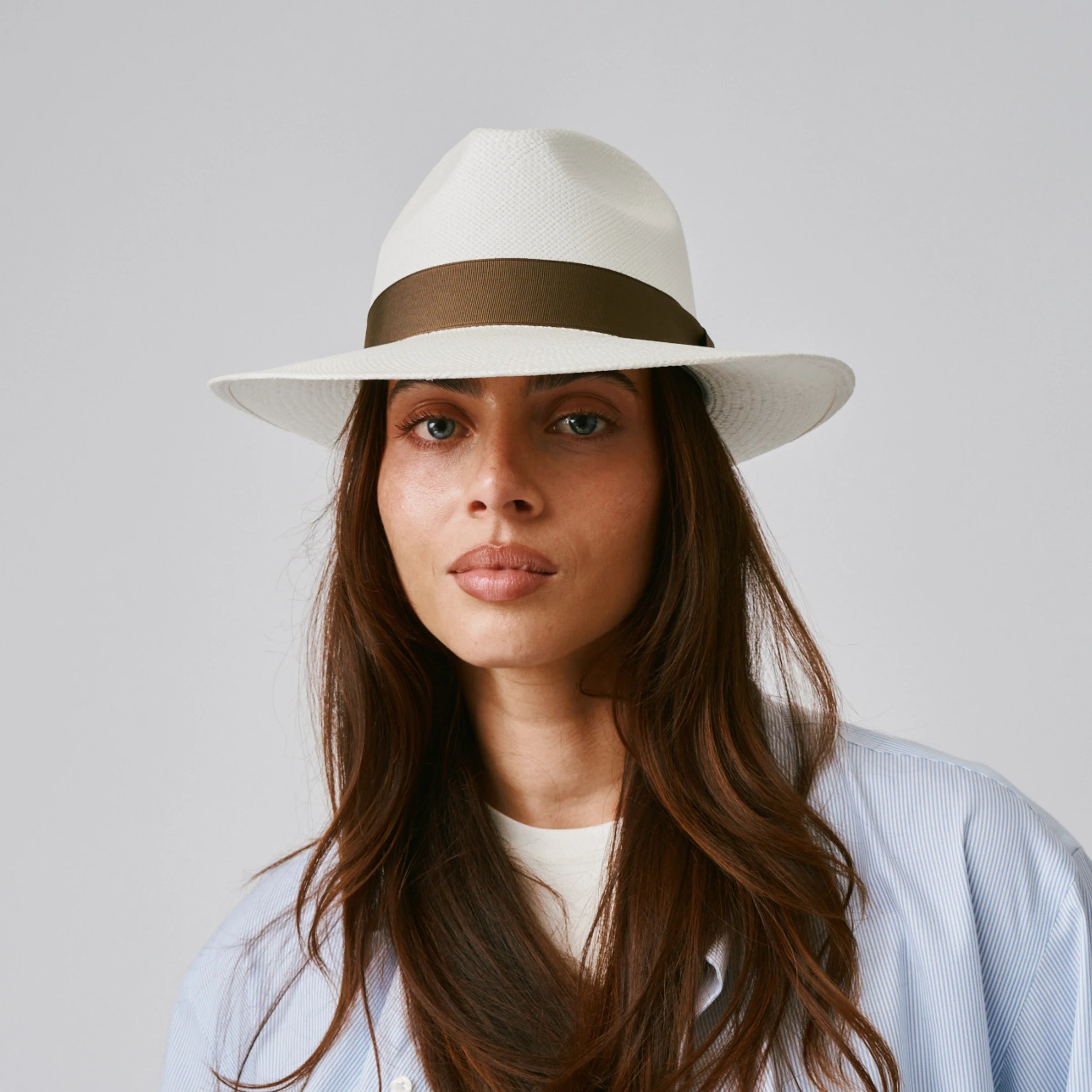 Woman wearing a Camilo Classic Cream / Fawn Panama hat and blue shirt against a plain background.