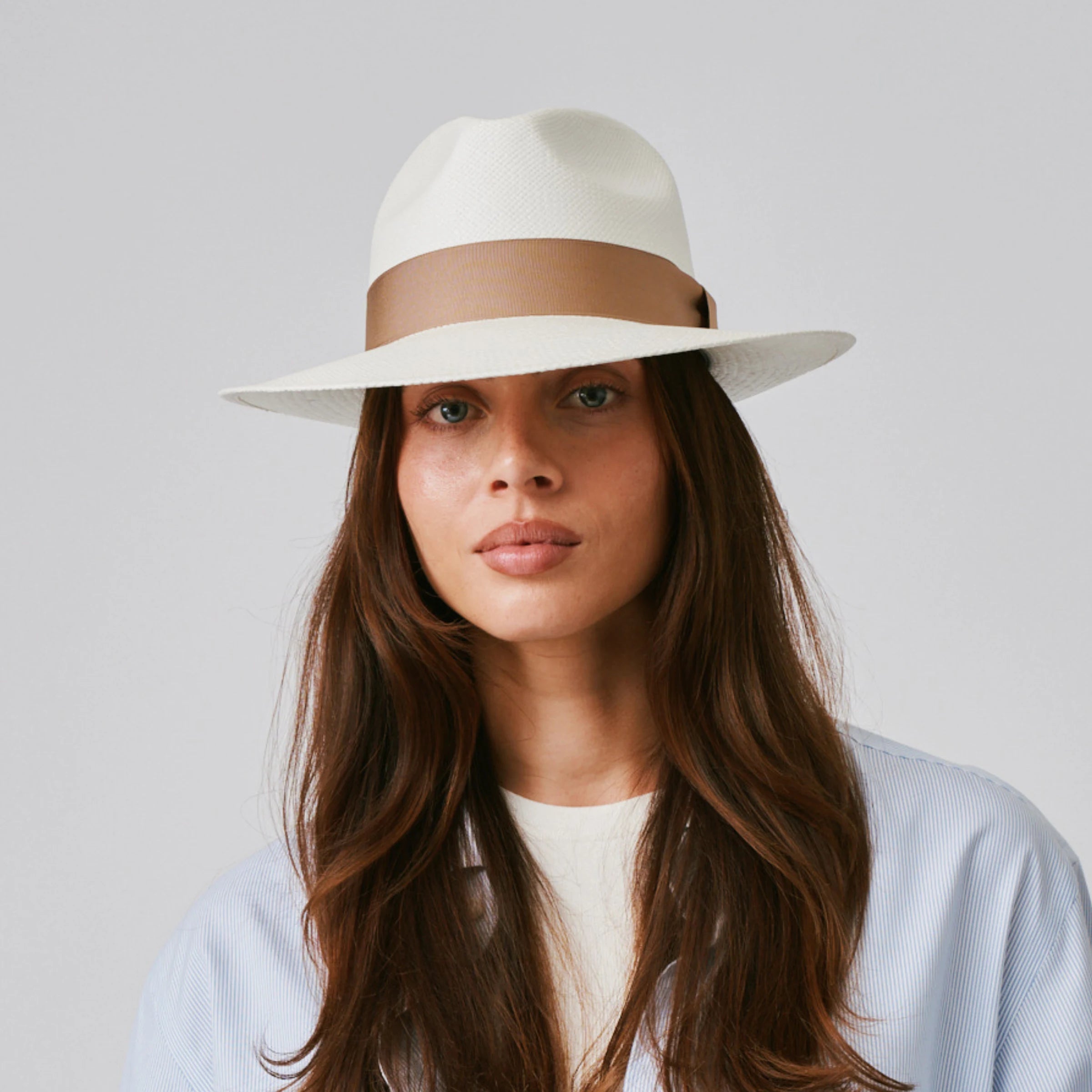Woman wearing a Camilo Classic Cream / Tan Panama hat and a blue shirt against a plain background.
