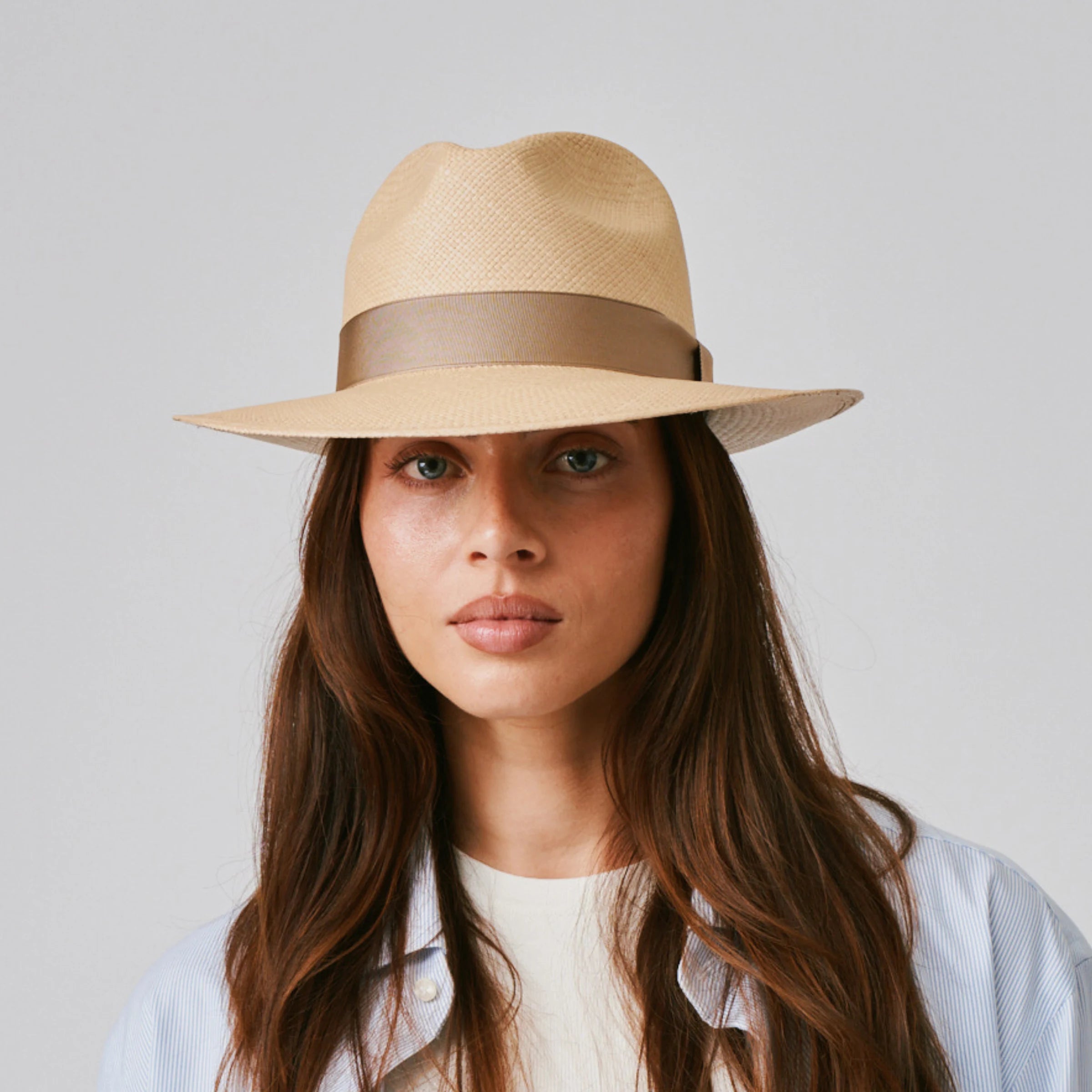 Woman wearing a Camilo Classic Sand / Taupe Panama hat and blue shirt against a plain background.