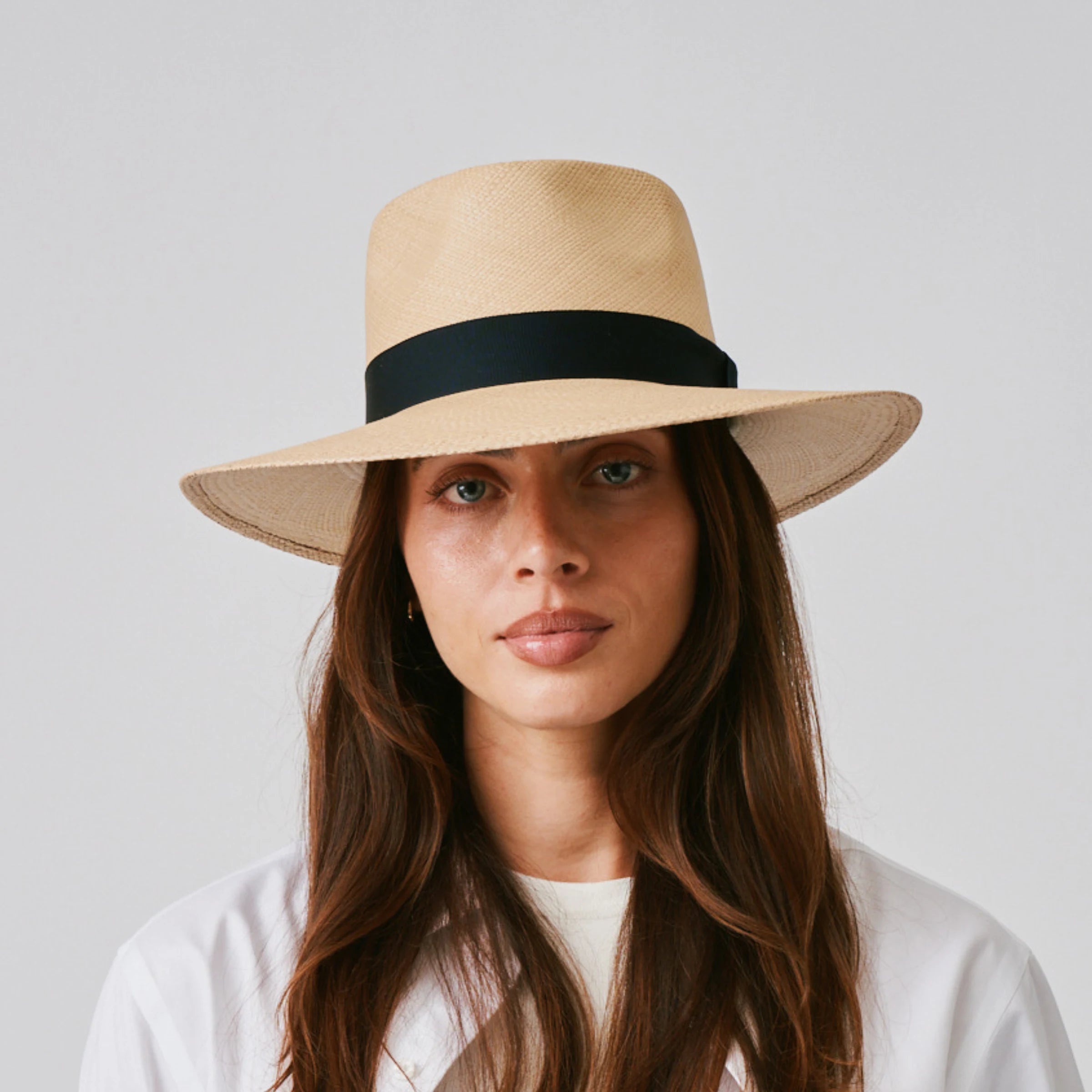 Woman wearing a Country Sand / Marine Panama hat and white tee against a plain background.