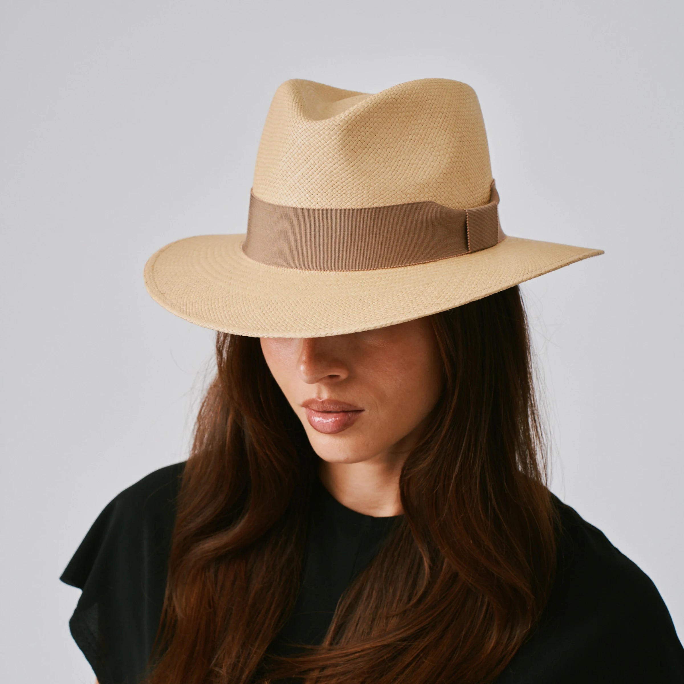Woman wearing a Executive Sand / Oat Panama hat against a plain background.