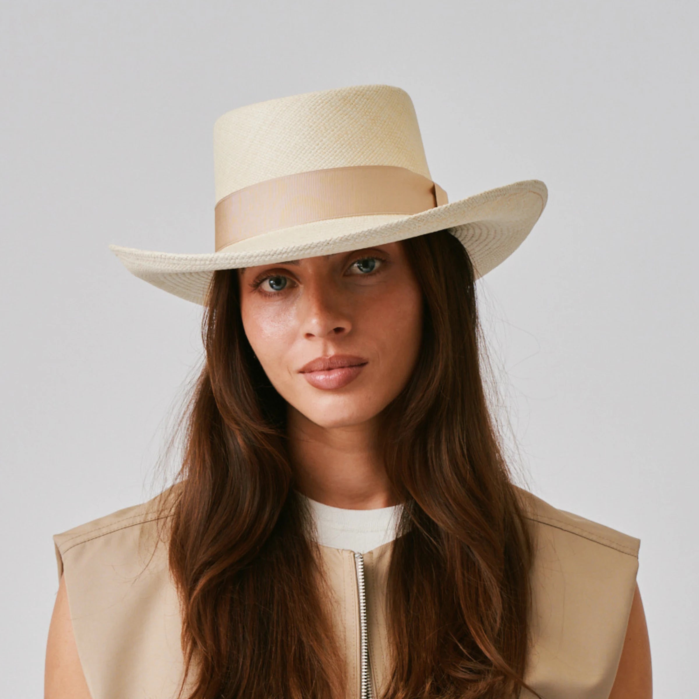 Woman wearing a Gambler Natural / Bone Panama hat and a beige vest against a plain background.