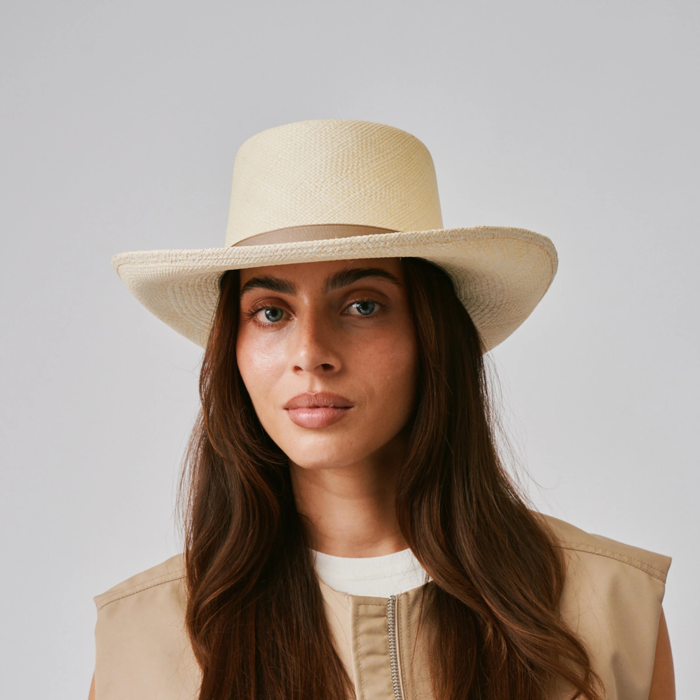 Woman wearing a Gambler Natural / Taupe Panama hat and beige top against a plain background.