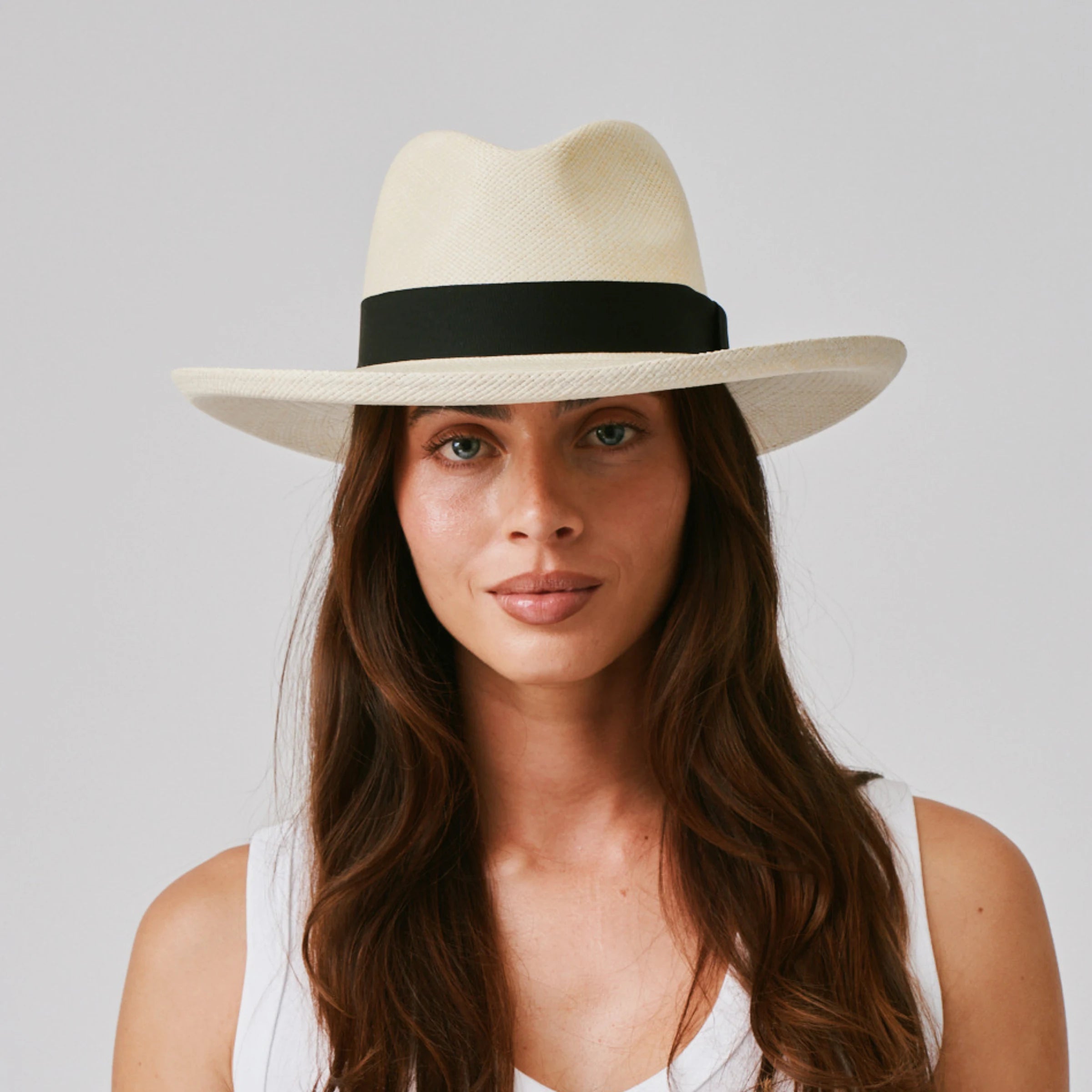 Woman wearing a Grand Planter Natural / Black Panama hat and white singlet against a plain background.
