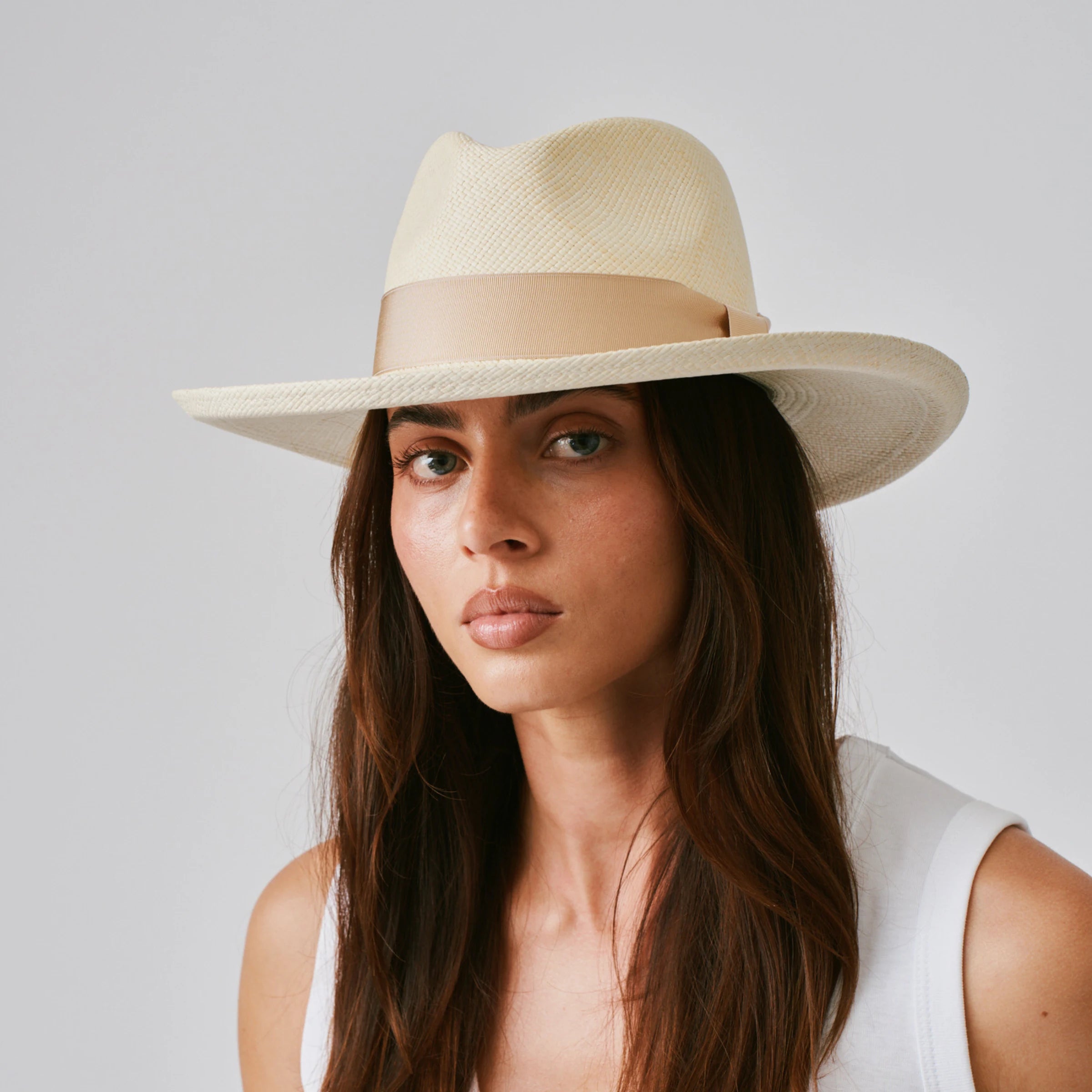 Woman wearing a Grand Planter Natural / Bone Panama hat against a plain background.