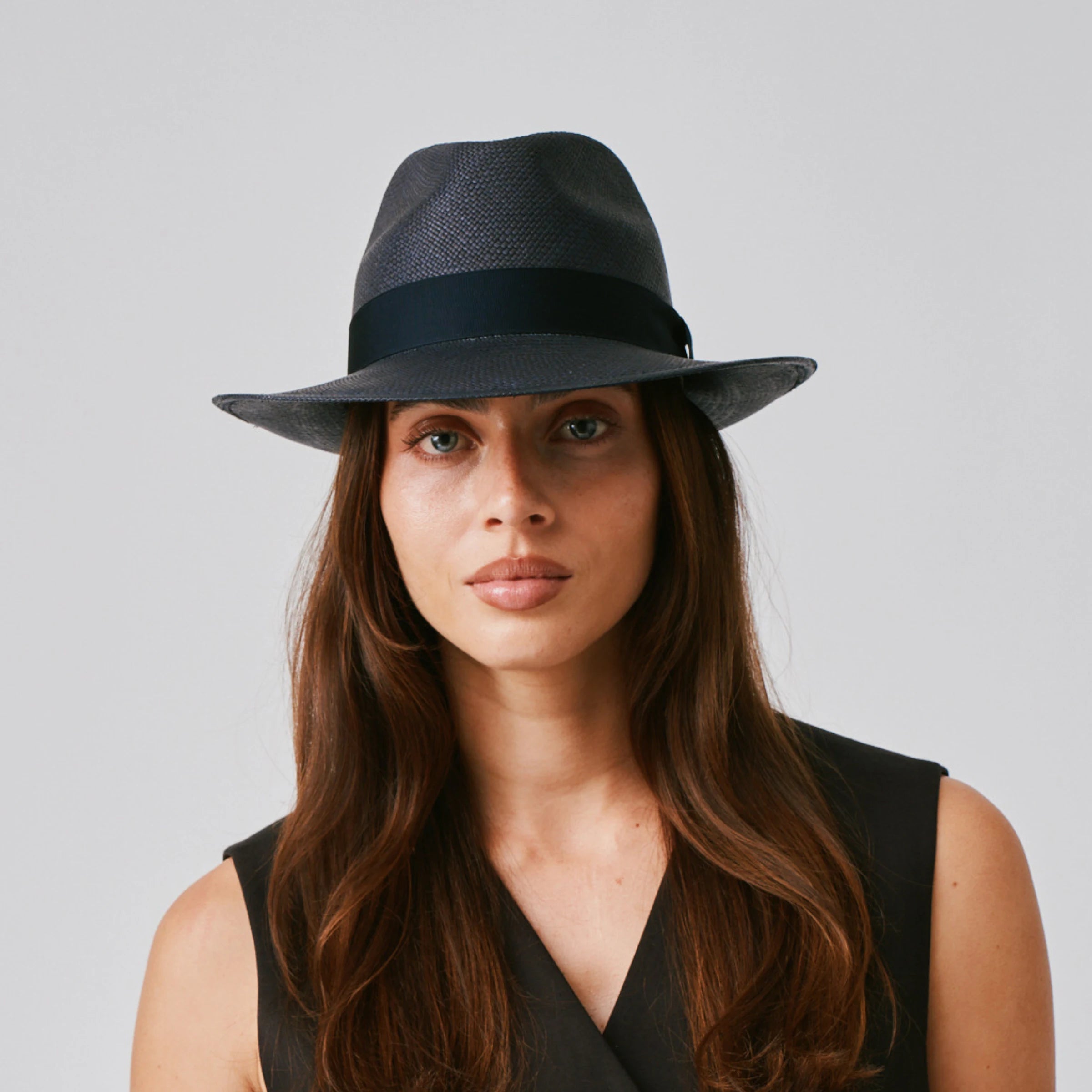 Woman wearing a New Fedora Navy / Marine Panama hat and black top against a plain background.