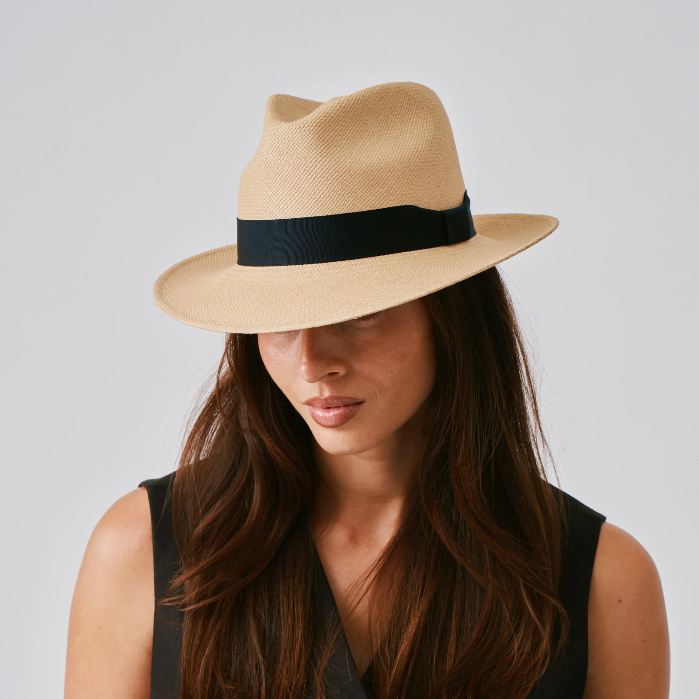 Woman wearing a New Fedora Sand / Marine Panama hat against a plain background.