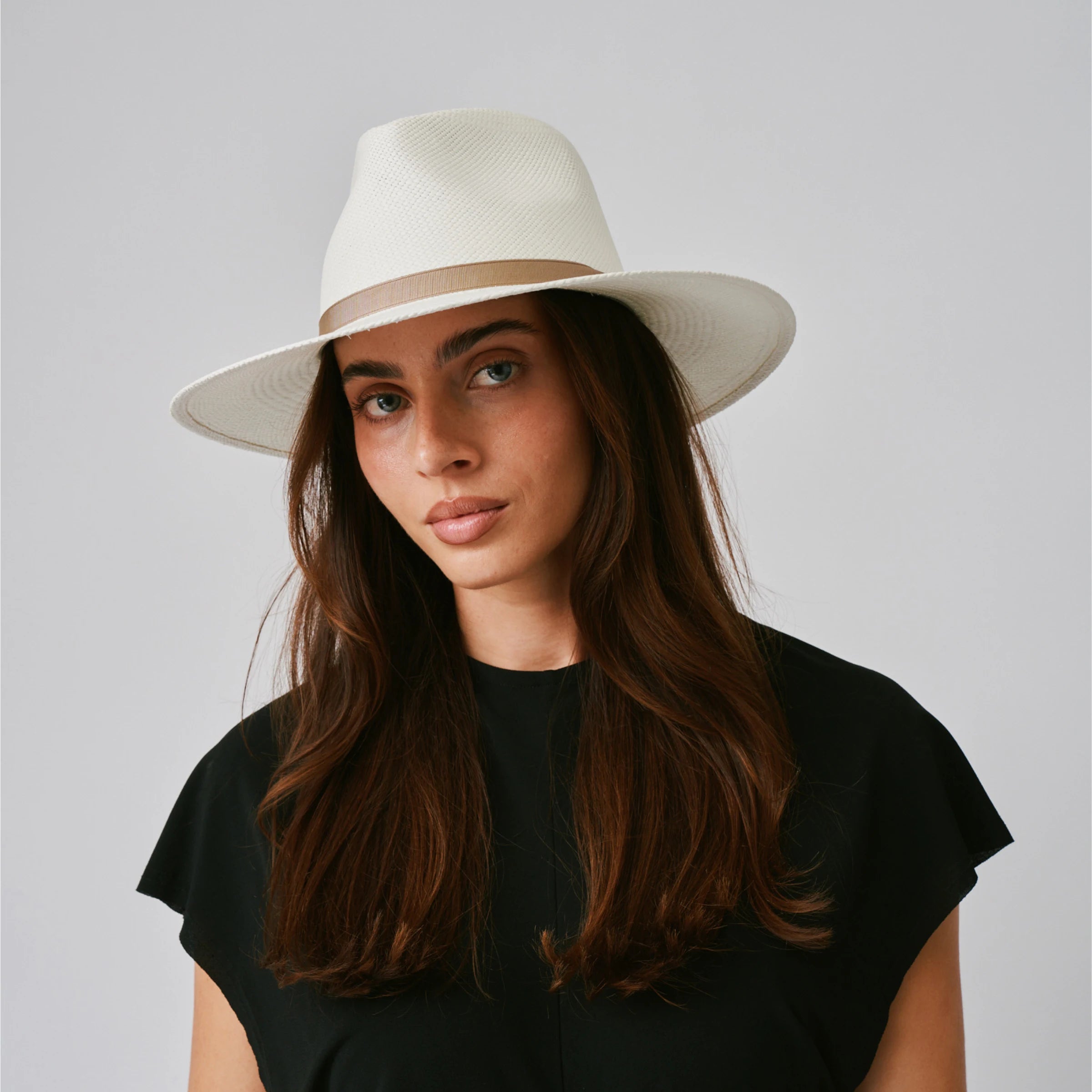 Woman wearing a Vita Cream / Tan Panama hat against a plain background.