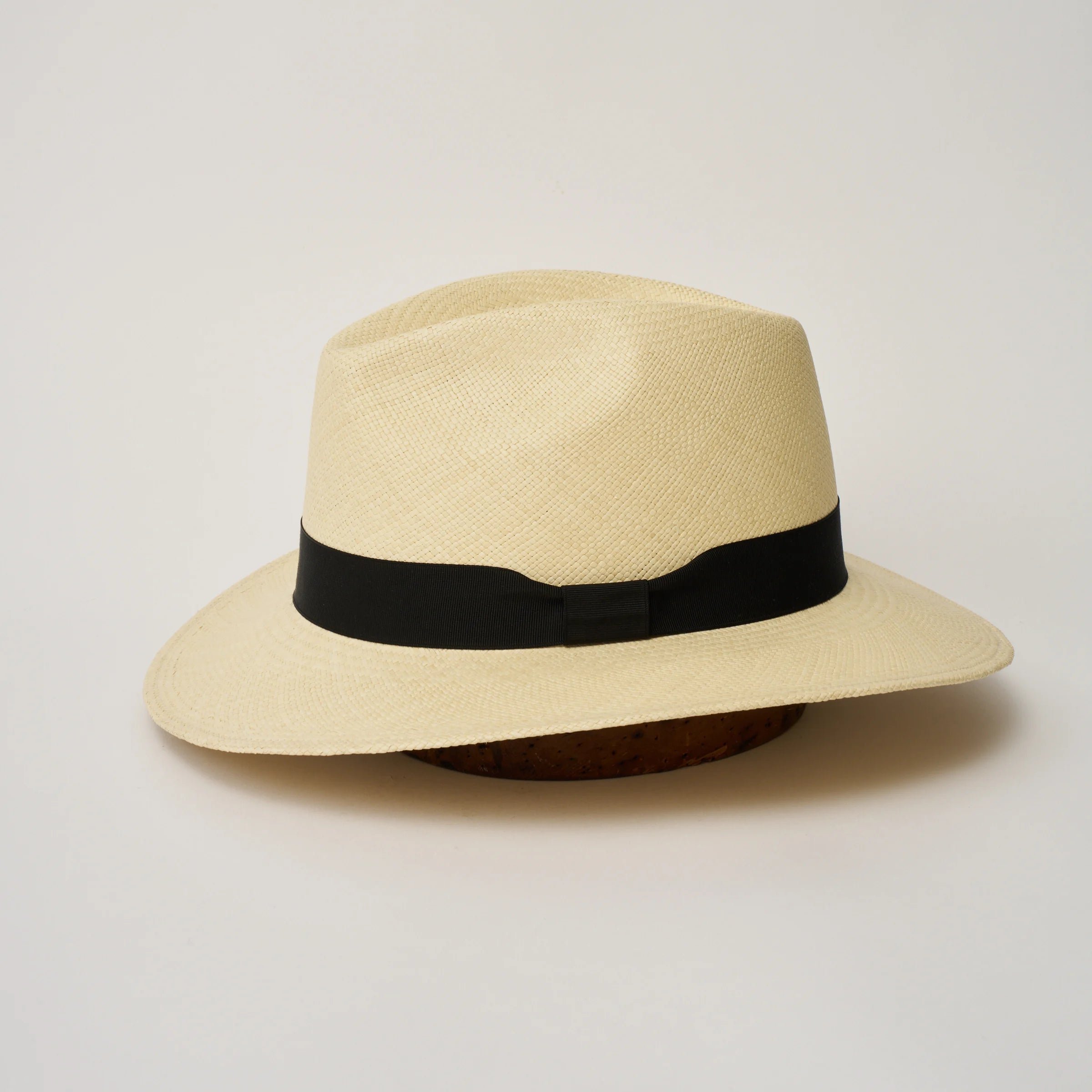 Studio image of the Camilo City Executive Natural coloured Panama Hat with Black trim taken from the side, showing brim and ribbon finish.