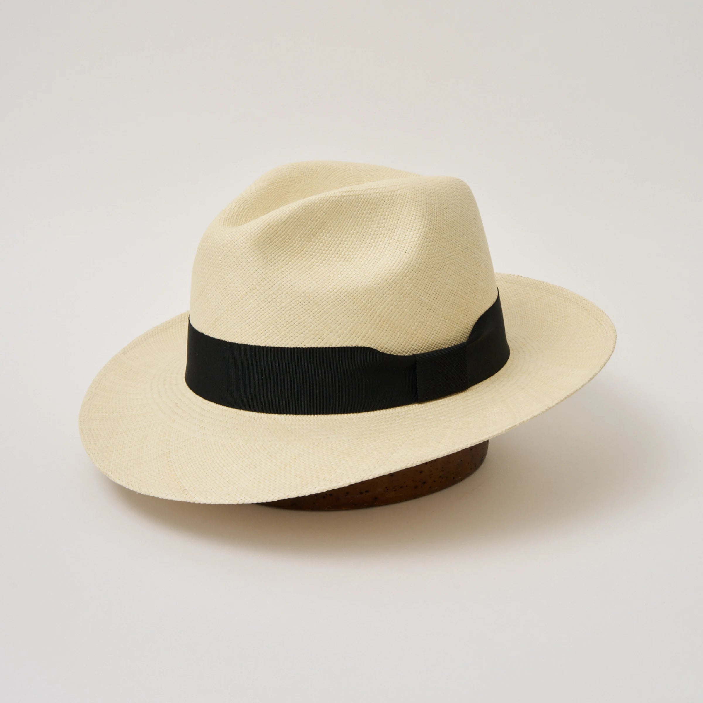 Studio image, angle view of the Camilo Classic Fino Natural coloured Panama Hat with Black trim, showing the crown crease and pinch.