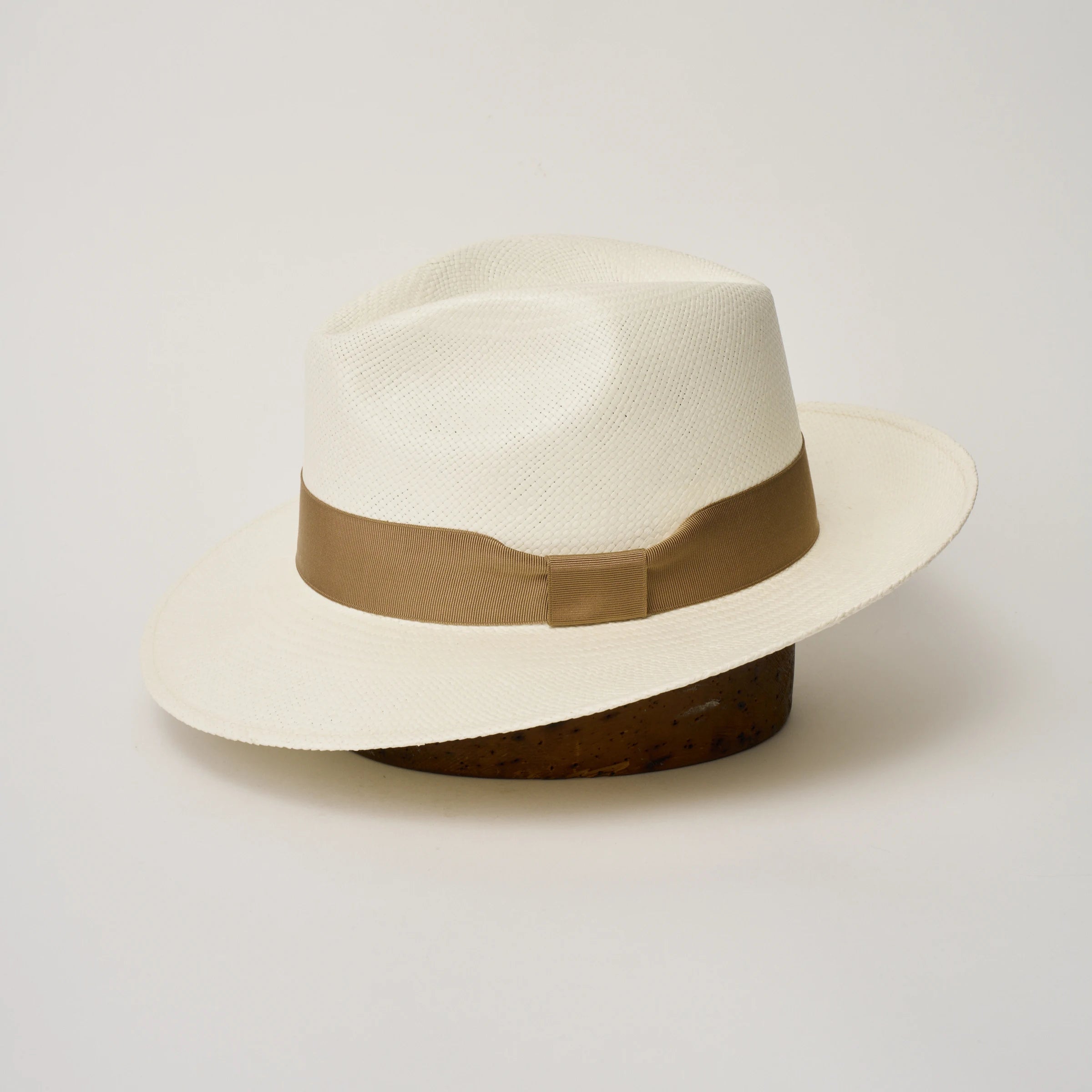 Studio image of the Camilo Classic Cream coloured Panama Hat with Tan trim shown from the side, showing the brim shape and ribbon finish.