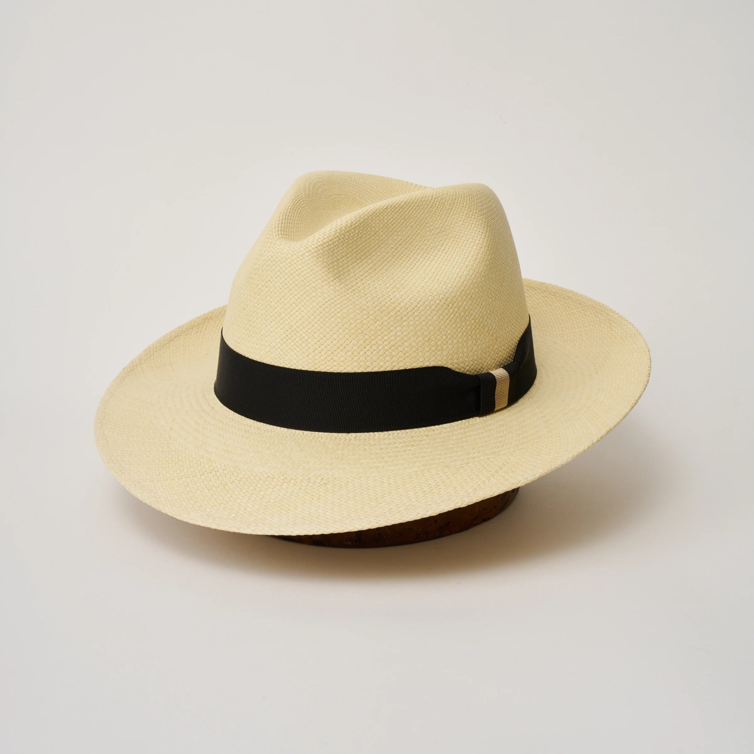 Studio image of the Camilo Classic Natural coloured Panama Hat with Black trim, angled showing the crown shape, front crease and ribbon details.