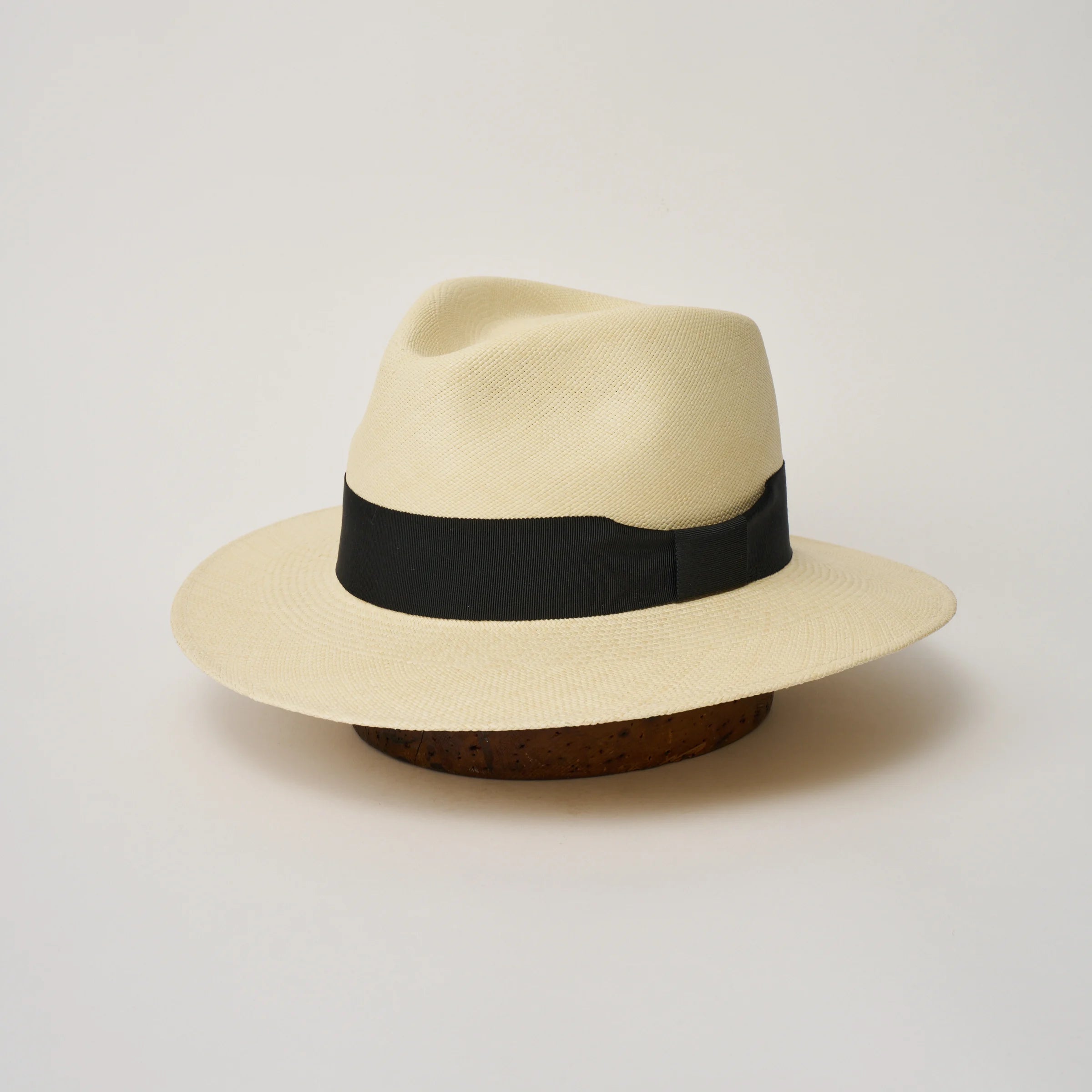 Studio image of the Camilo Executive Fino Natural coloured Panama Hat with Black trim, angled showing the crown shape, front crease and ribbon details.