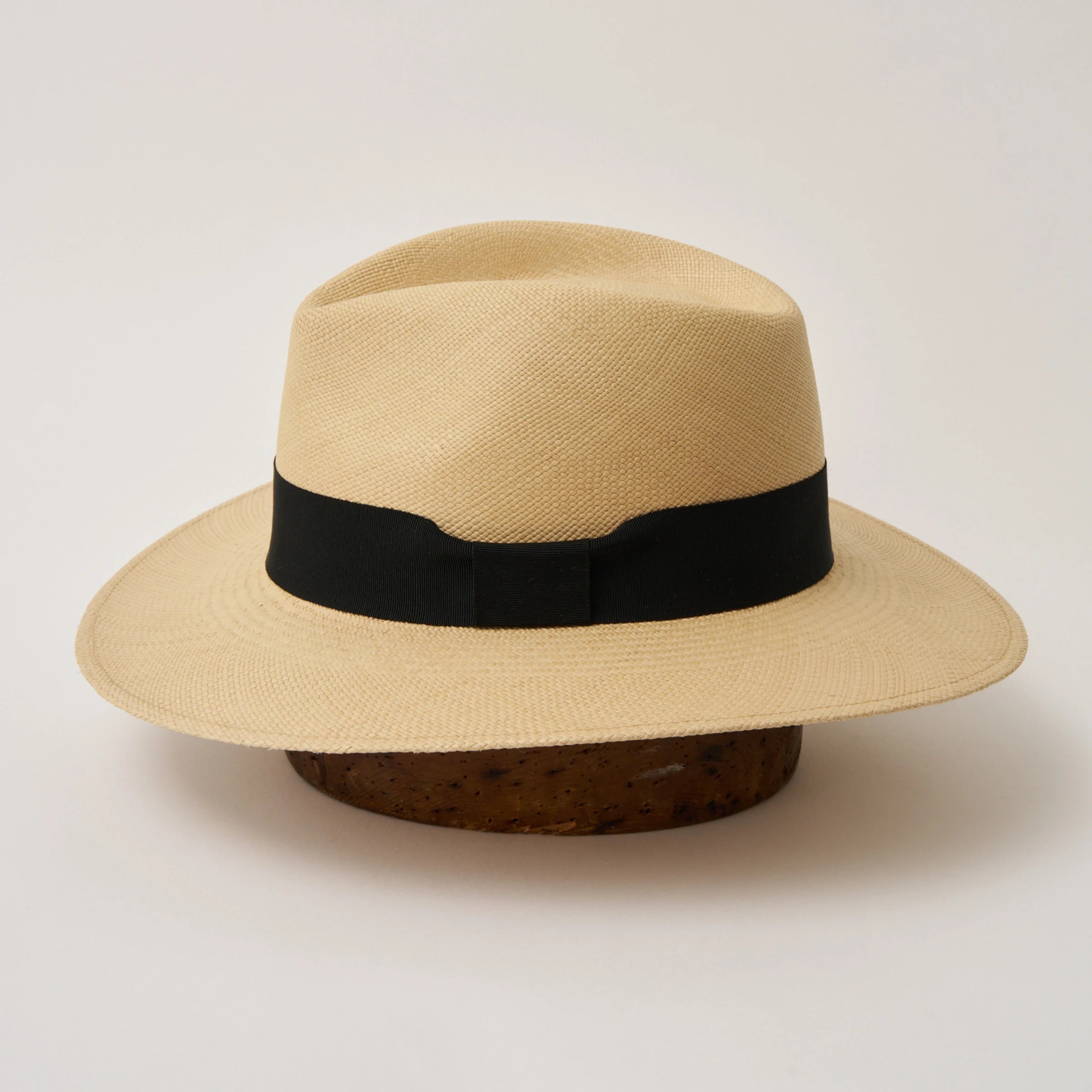 Studio image of the Camilo Executive Fino
Sand coloured Panama Hat with Black trim shown from the side, showing the brim shape and ribbon finish.