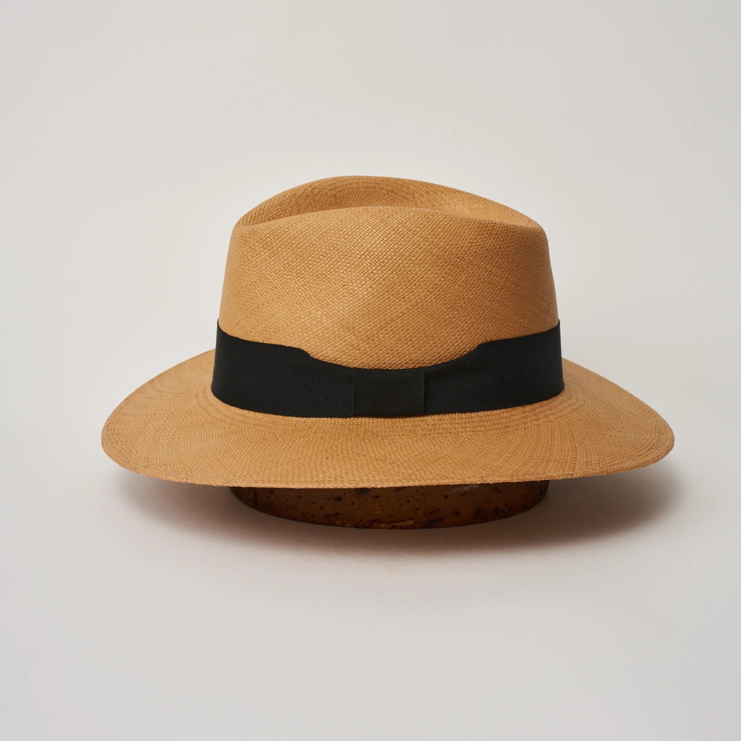 Studio image of the Camilo Executive Fino
Toffee coloured Panama Hat with Black trim shown from the side, showing the brim shape and ribbon finish.
