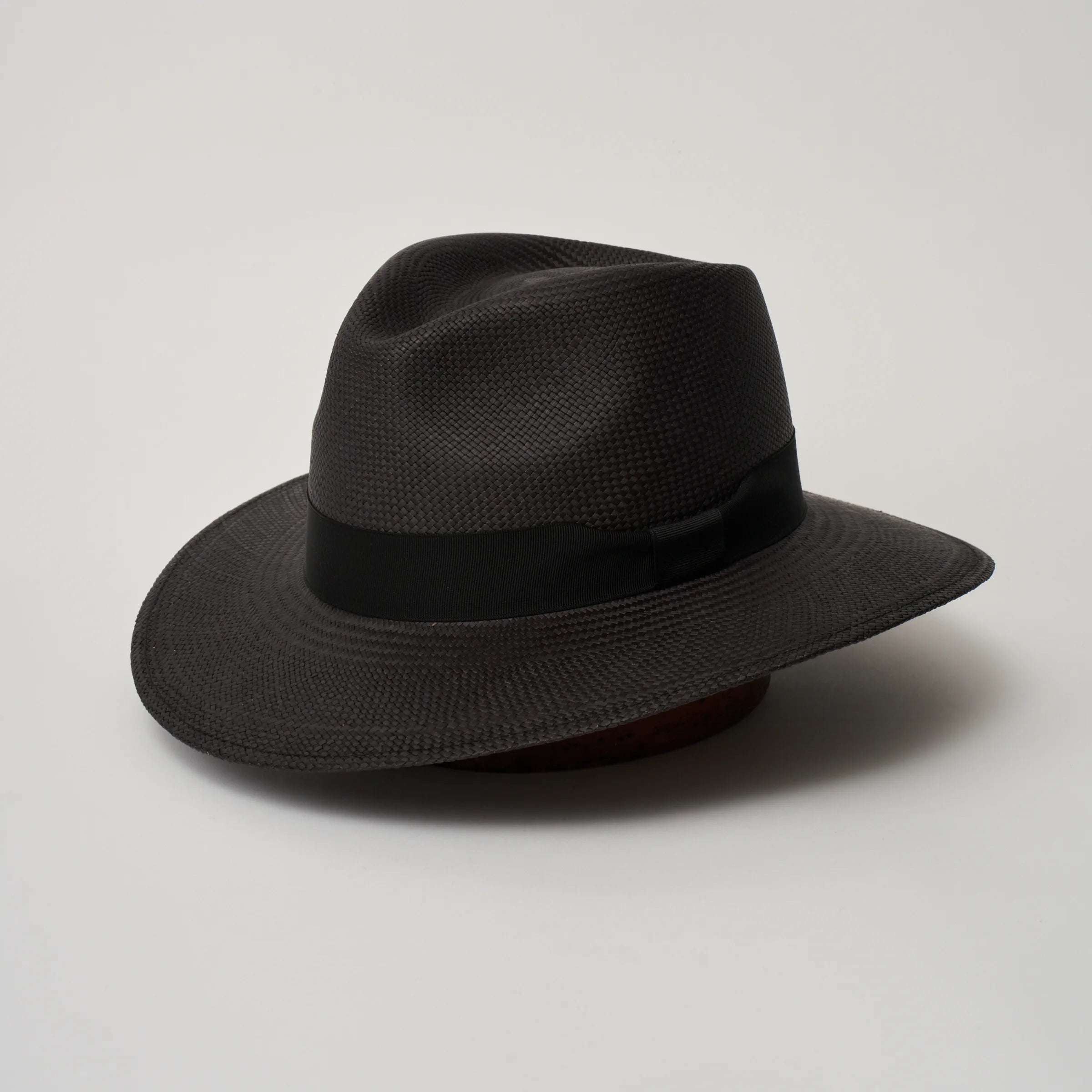 Studio image of the Camilo Executive Black coloured Panama Hat with Black trim, angled showing the crown shape, front crease and ribbon details.