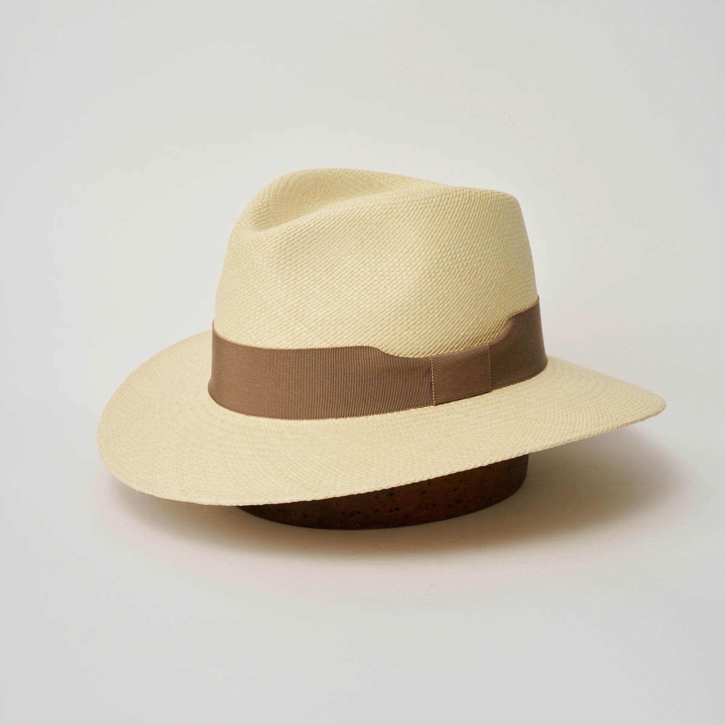 Studio image of the Camilo Executive Natural coloured Panama Hat with Oat trim, angled showing the crown shape, front crease and ribbon details.