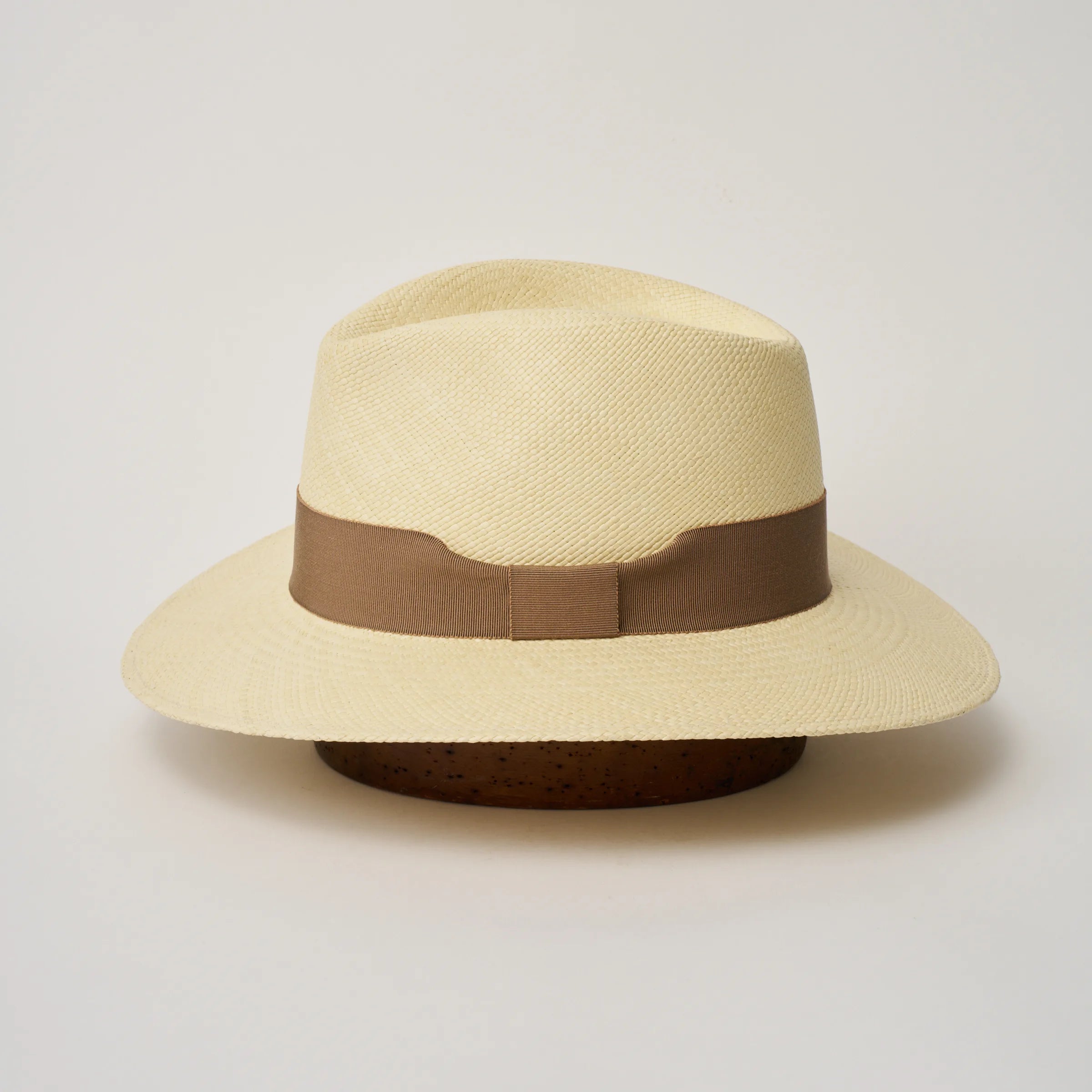 Studio image of the Camilo Executive 
Natural coloured Panama Hat with Oat trim shown from the side, showing the brim shape and ribbon finish.