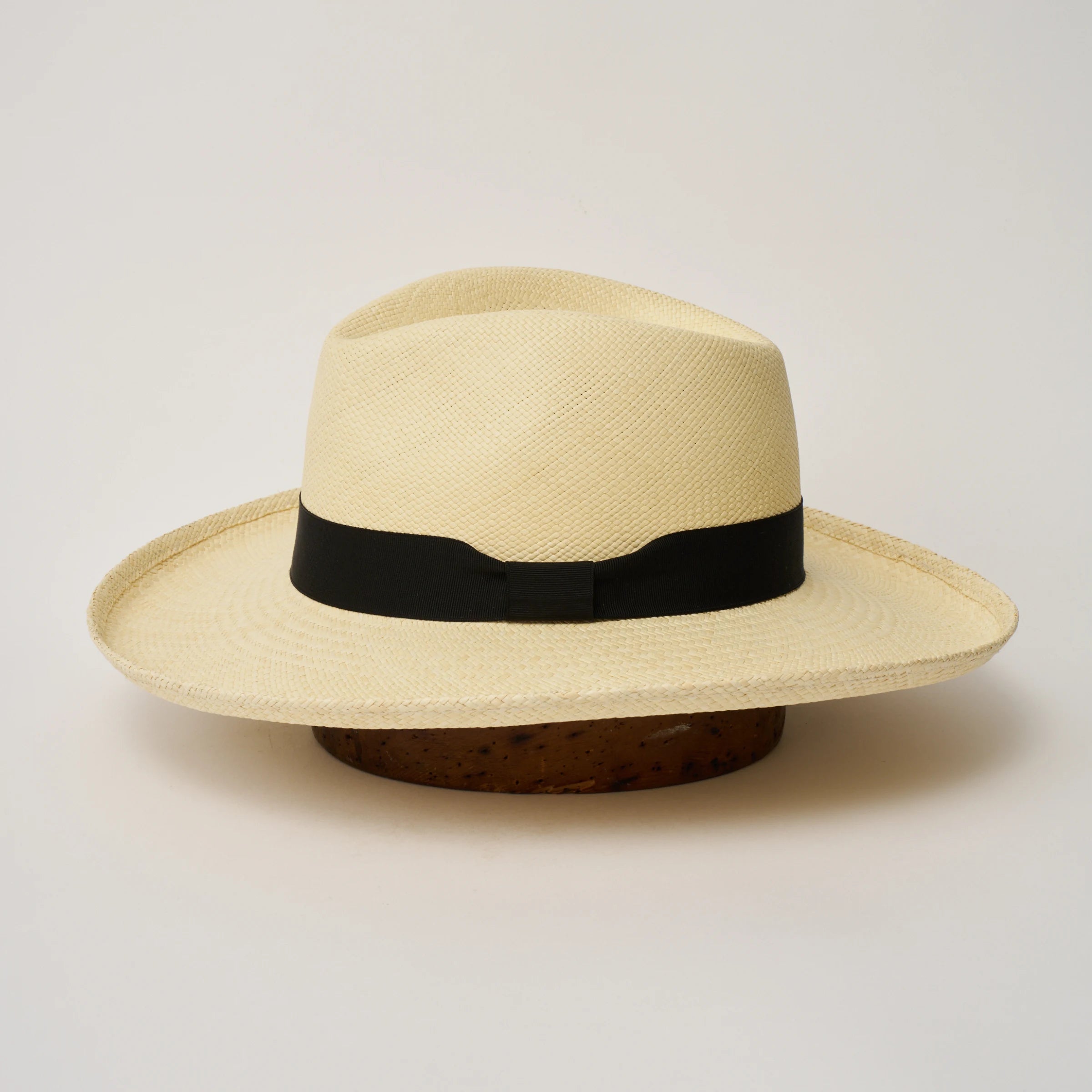 Studio image of the Camilo Grand Planter
Natural coloured Panama Hat with Black trim shown from the side, showing the brim shape and ribbon finish.