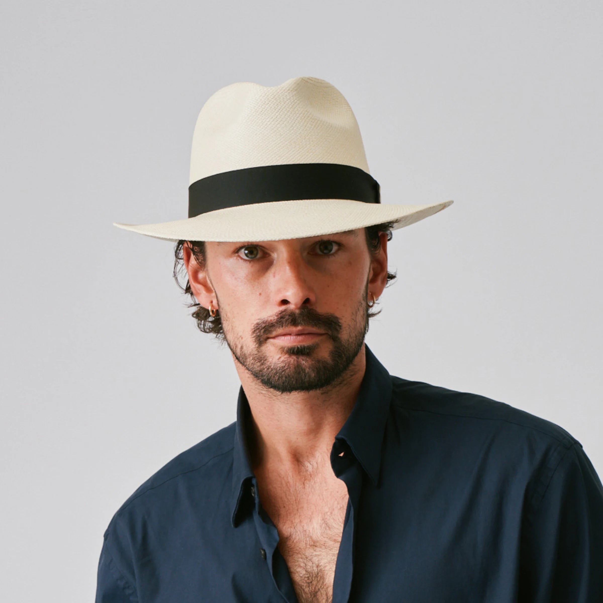 Man wearing a Camilo Classic Natural / Black Panama hat and navy shirt against a plain background.