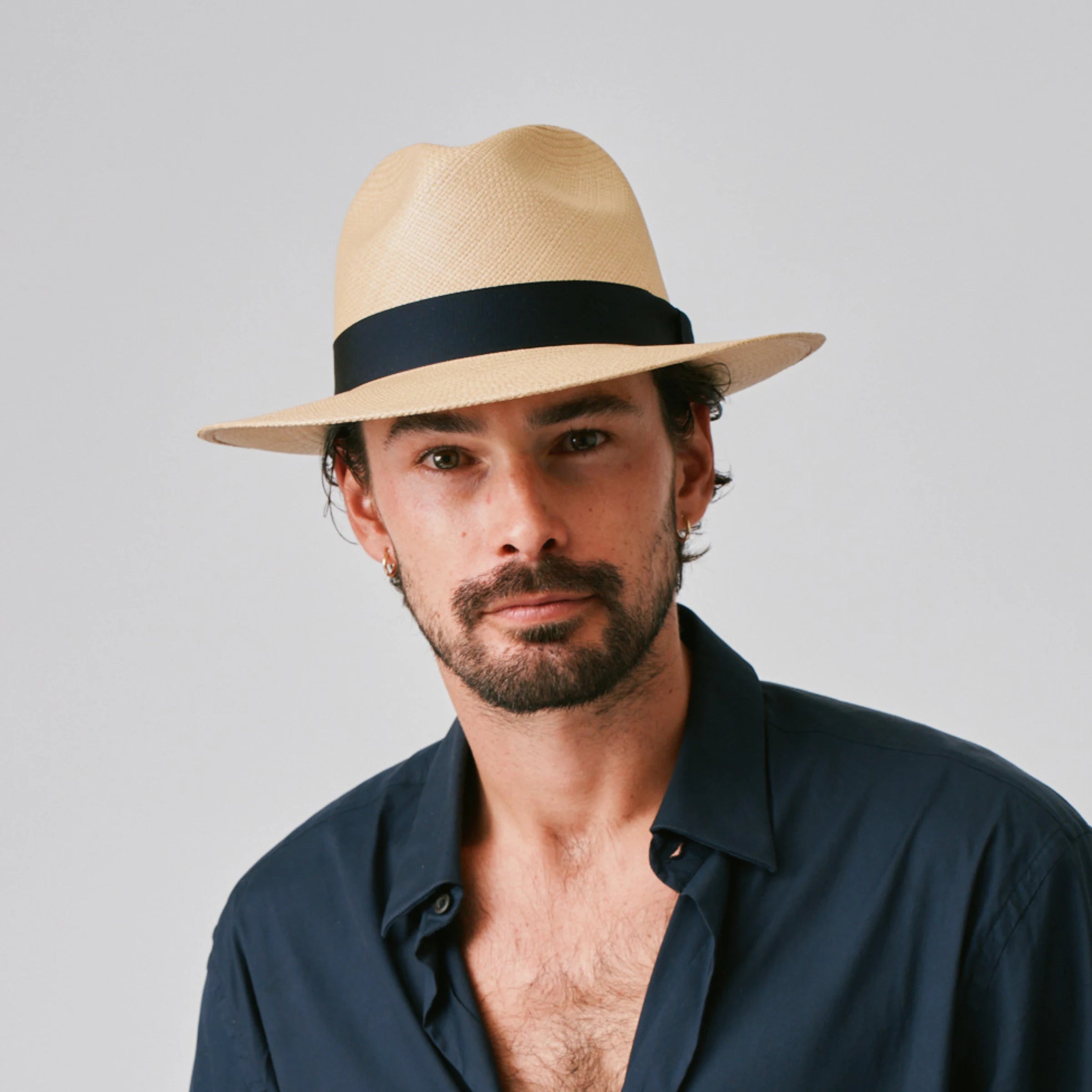 Man wearing a Camilo Classic Sand / Marine Panama hat and navy shirt against a plain background.